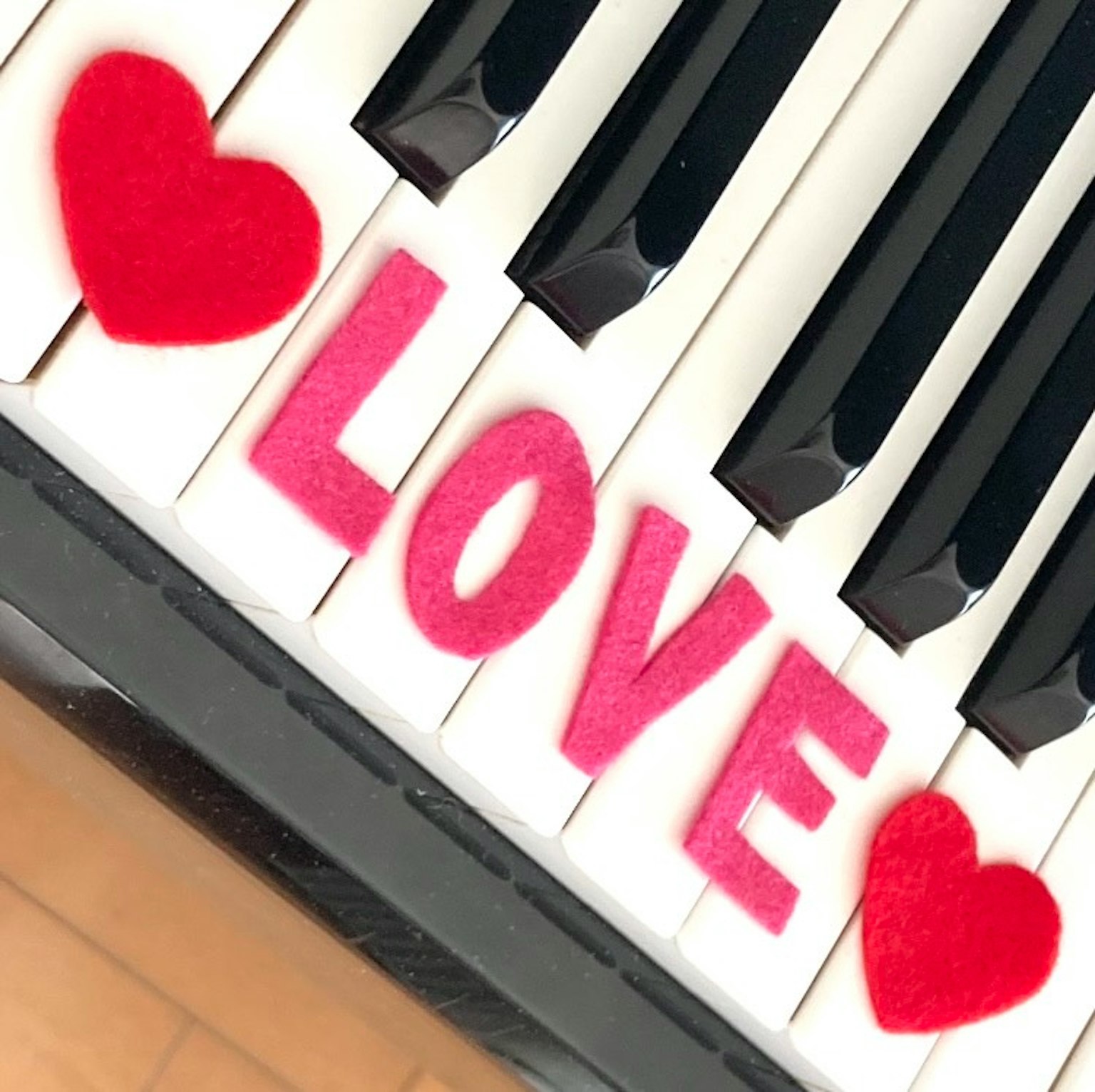 Cuori rossi e lettere rosa che formano LOVE sui tasti del pianoforte