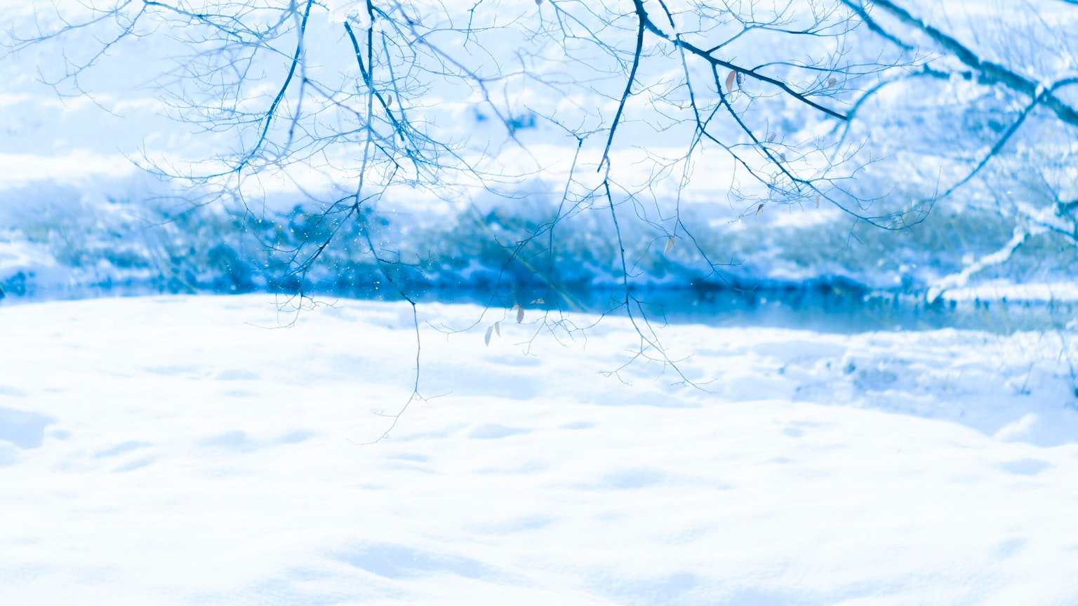 Snow-covered landscape with reflections of blue sky
