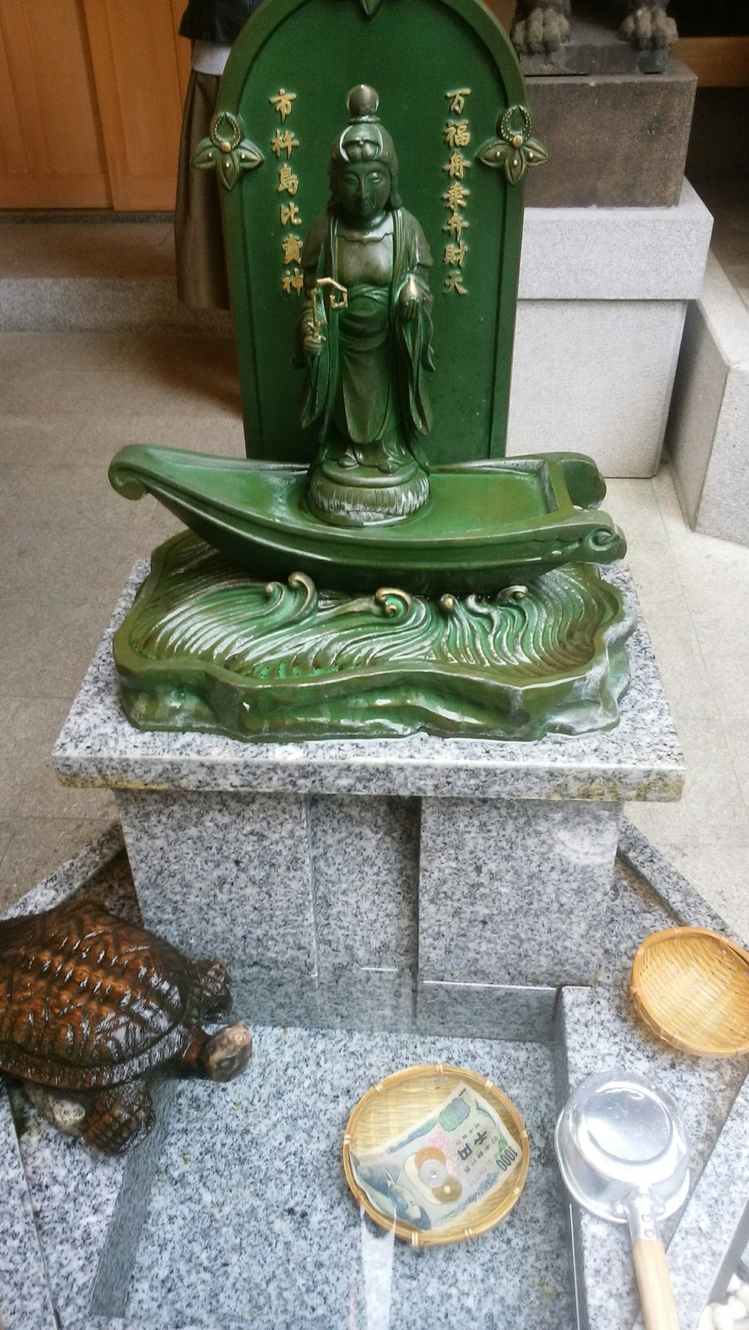 Green deity statue with turtle sculpture on altar