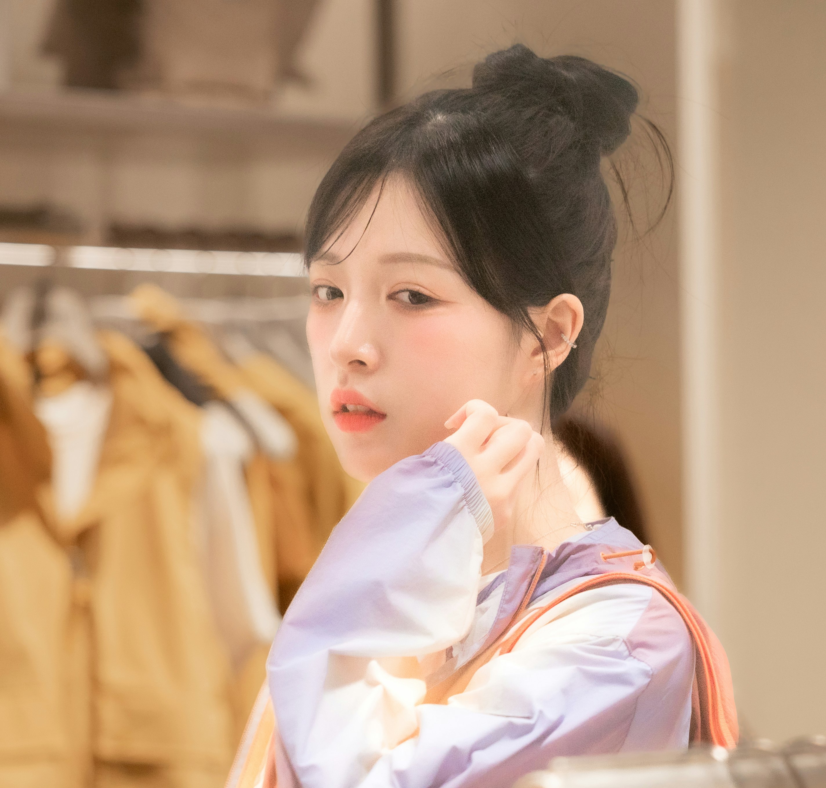 洋服店の棚の前で頬に手を添える子ども