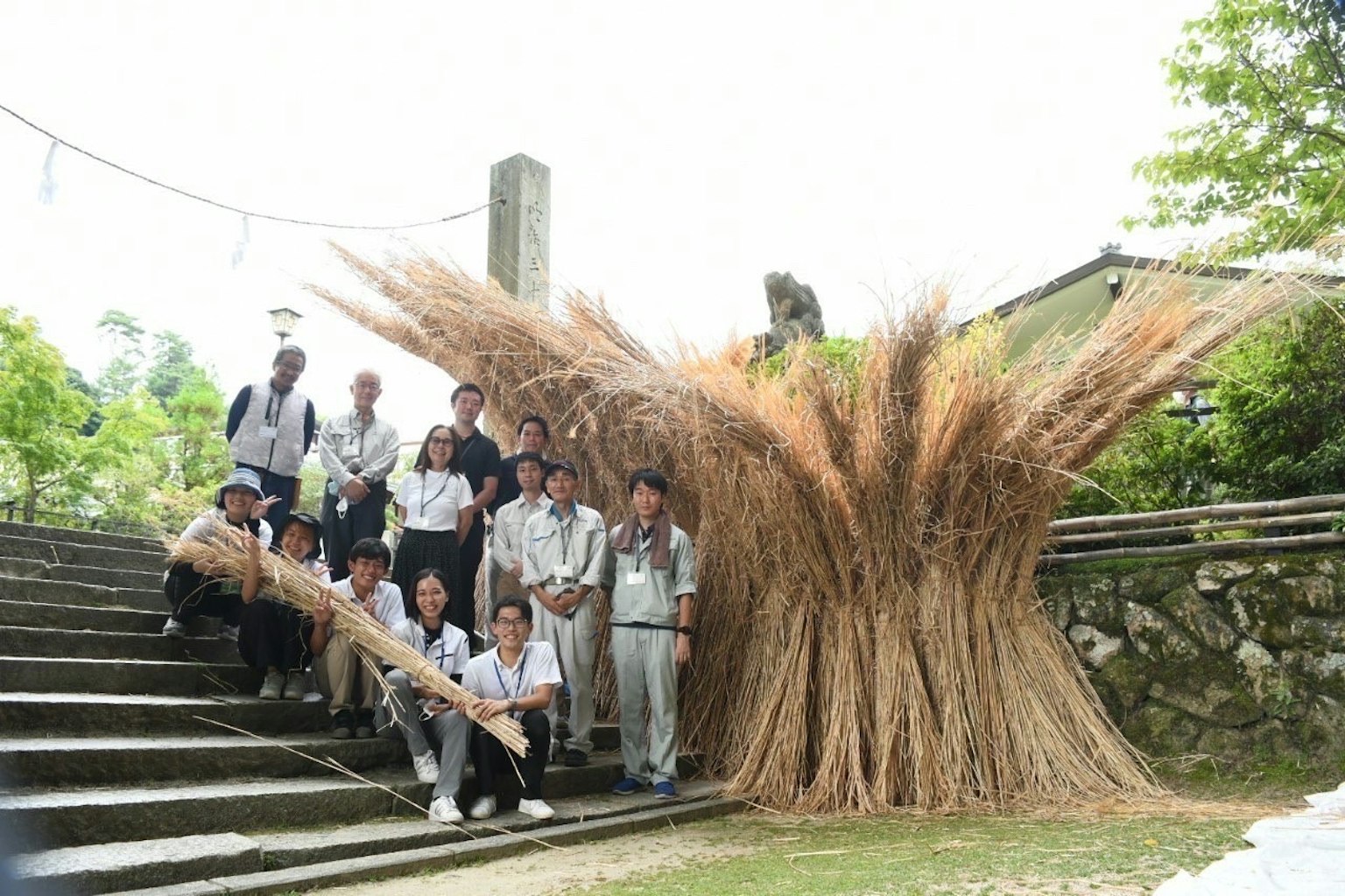 Group of people posing with a large straw sculpture