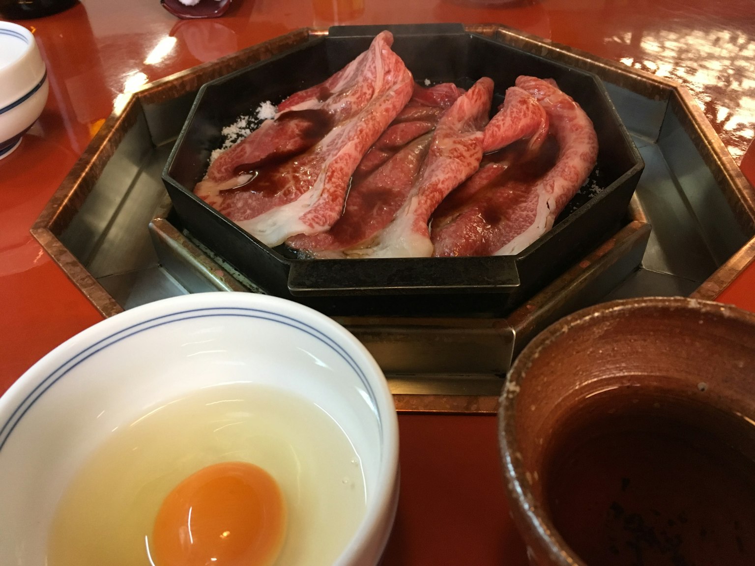Table with grilled meat and raw egg