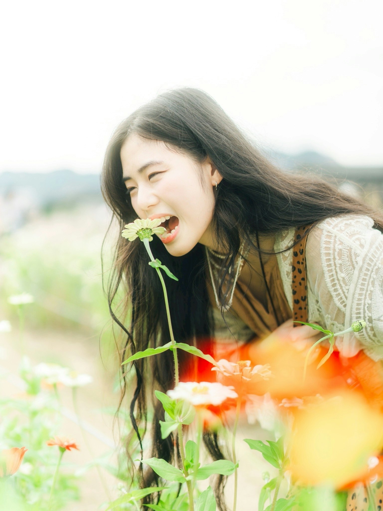 花畑で花を咥えた女性の笑顔