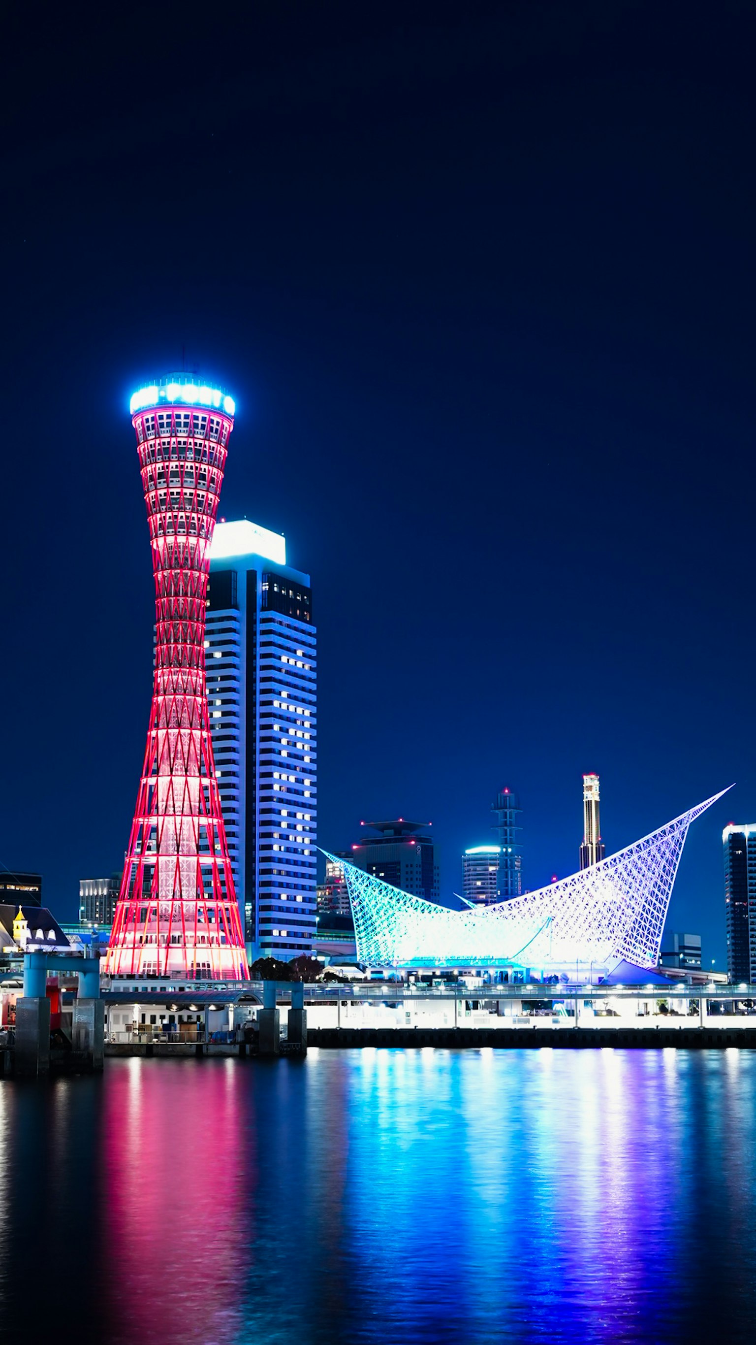 Đường chân trời ban đêm của Kobe với tháp cảng sáng và các tòa nhà Harborland