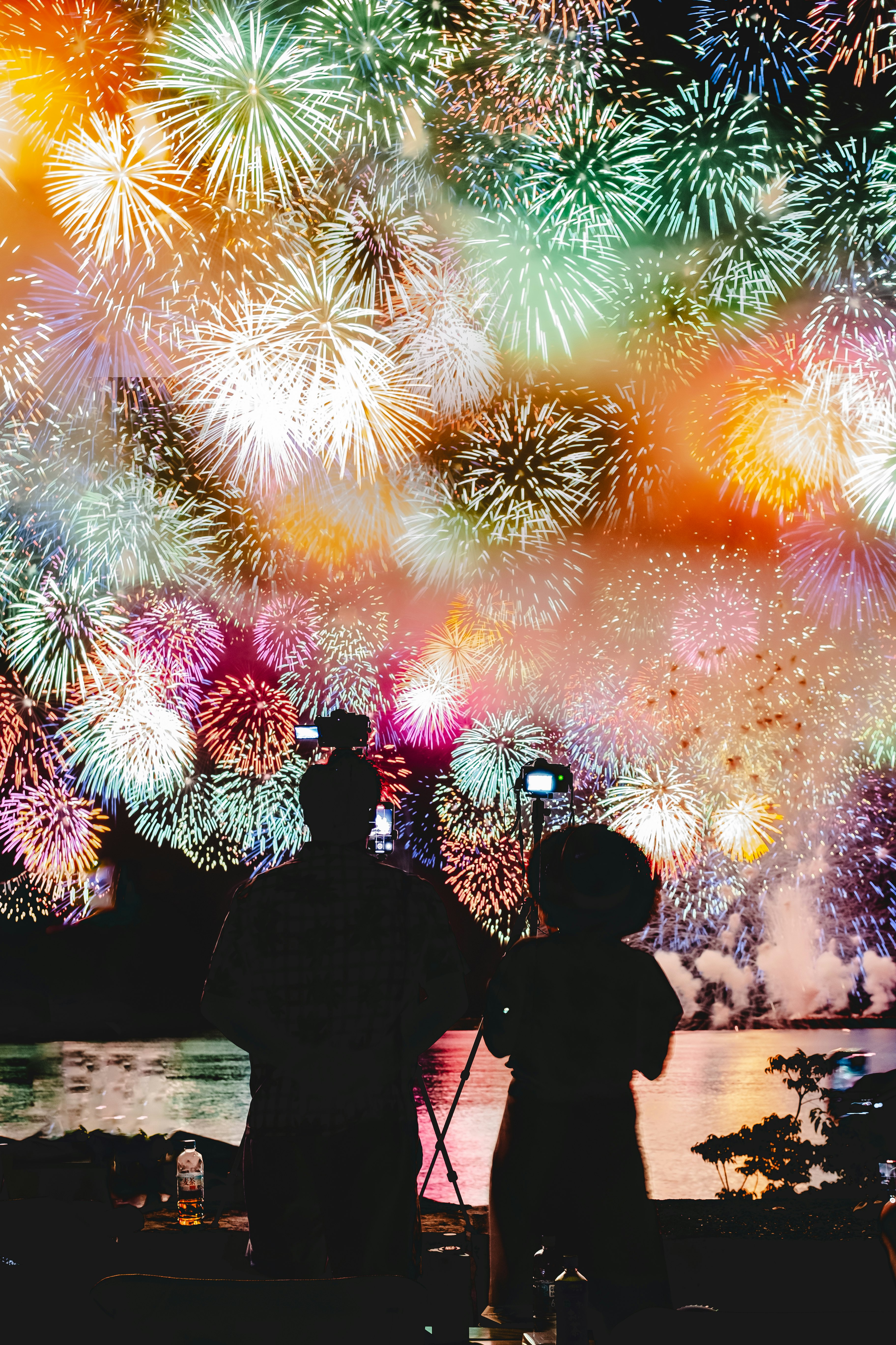 花火を見上げる人々のシルエットと夜空の大輪
