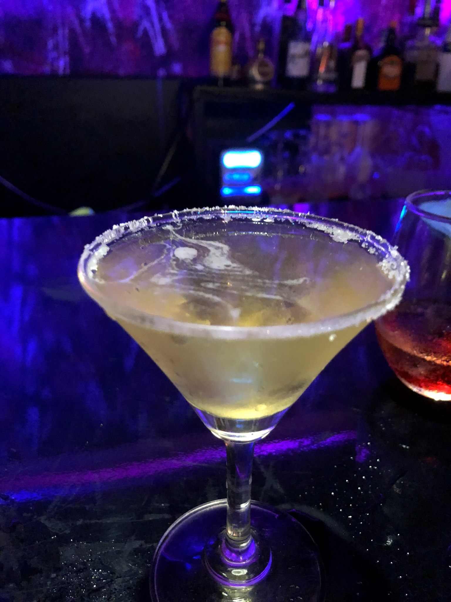 雞尾酒杯中裝有冰塊的瑪格麗塔飲品和鹽邊，背景是酒吧