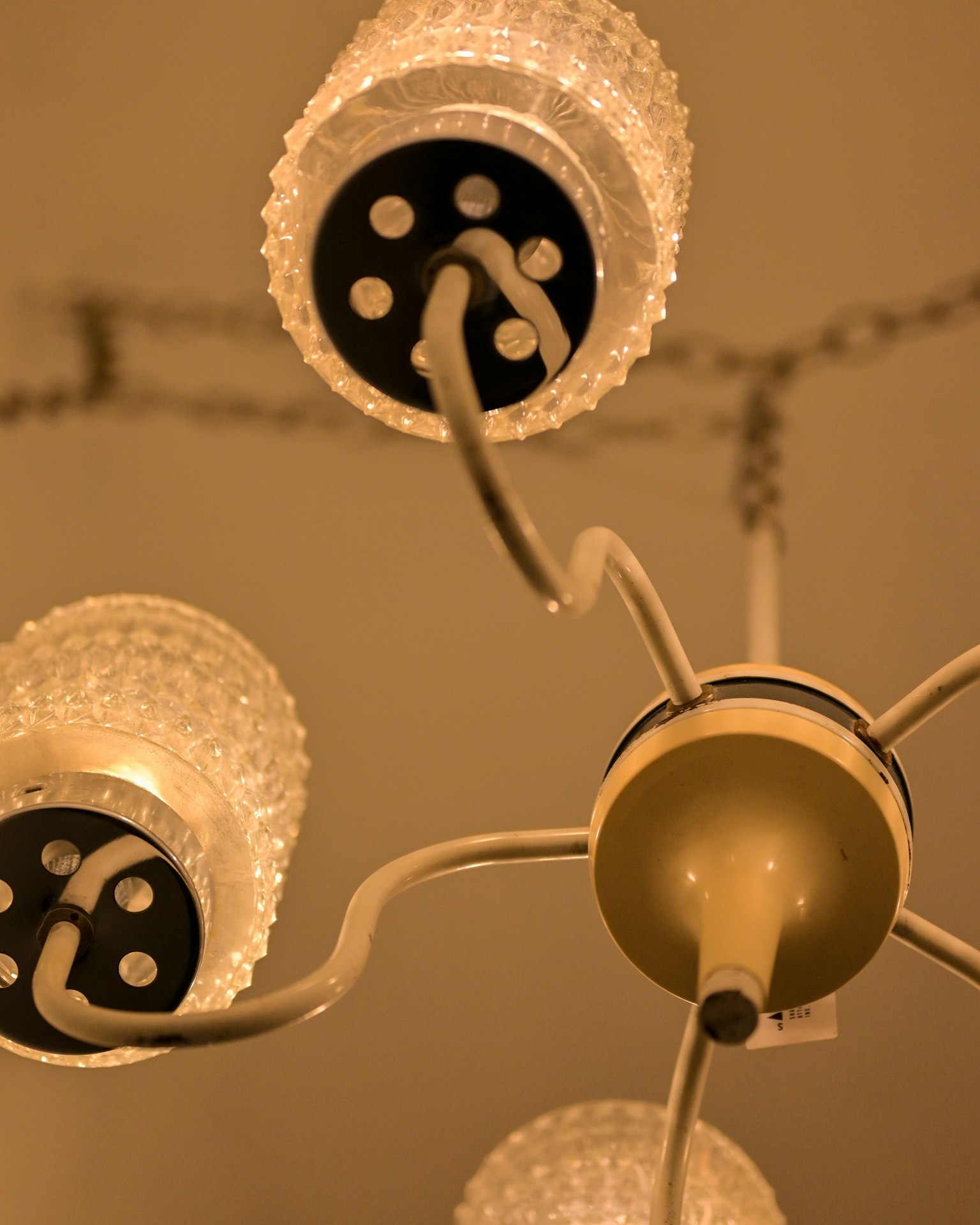 View from below a chandelier with transparent lamp shades and white arms