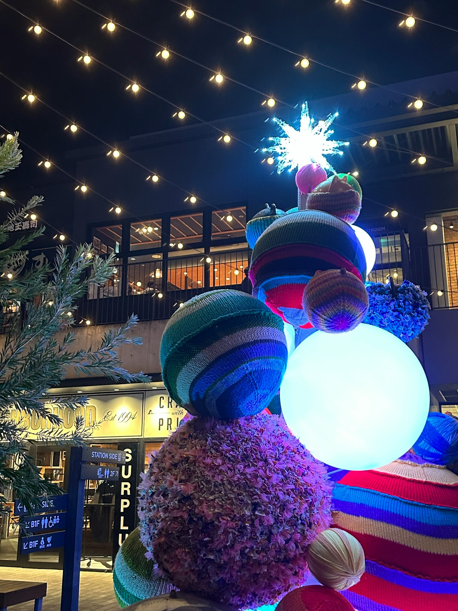 Weihnachtsbaumdekoration mit bunten Kugeln und einem sternförmigen Ornament bei Nacht
