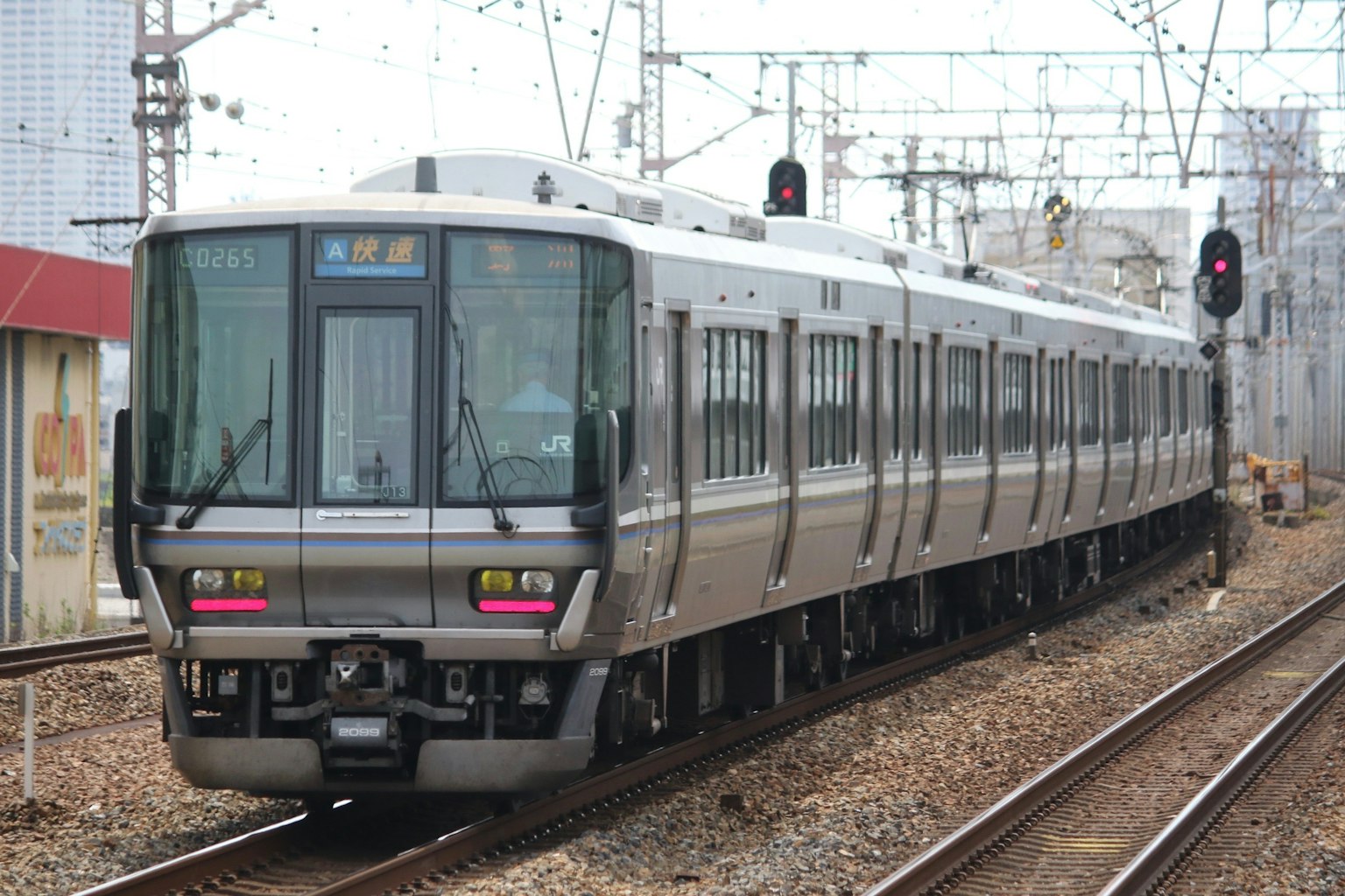 รถไฟสีเงินกำลังวิ่งบนรางพร้อมสัญญาณไฟแดงที่บอกให้หยุด