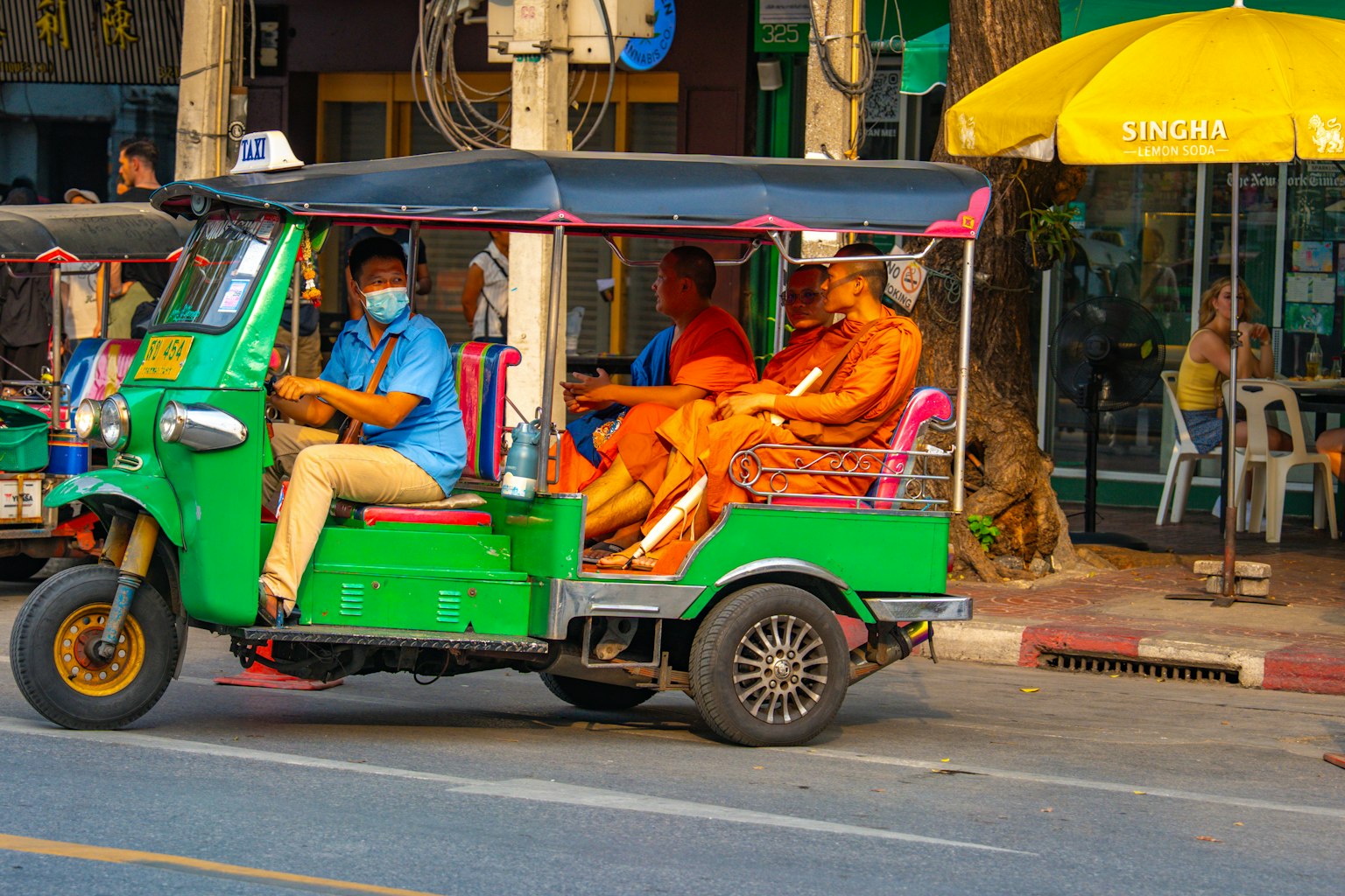 Un tuk-tuk verde con monjes y un conductor