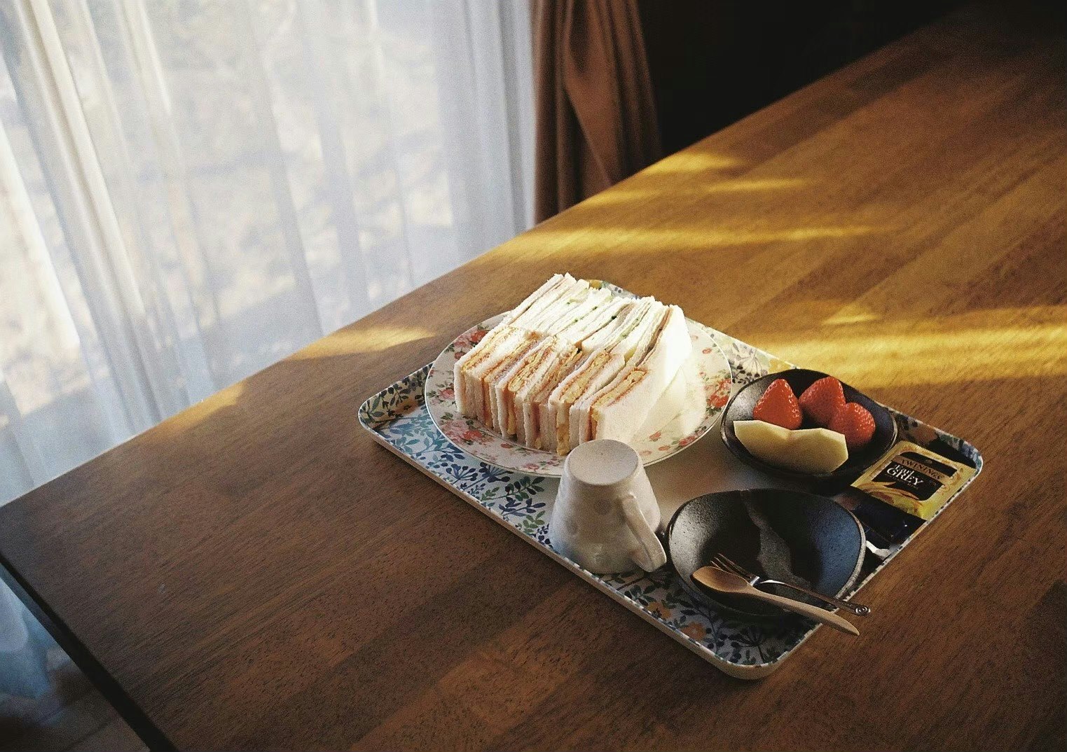 bandeja de sándwiches y postres sobre una mesa de madera