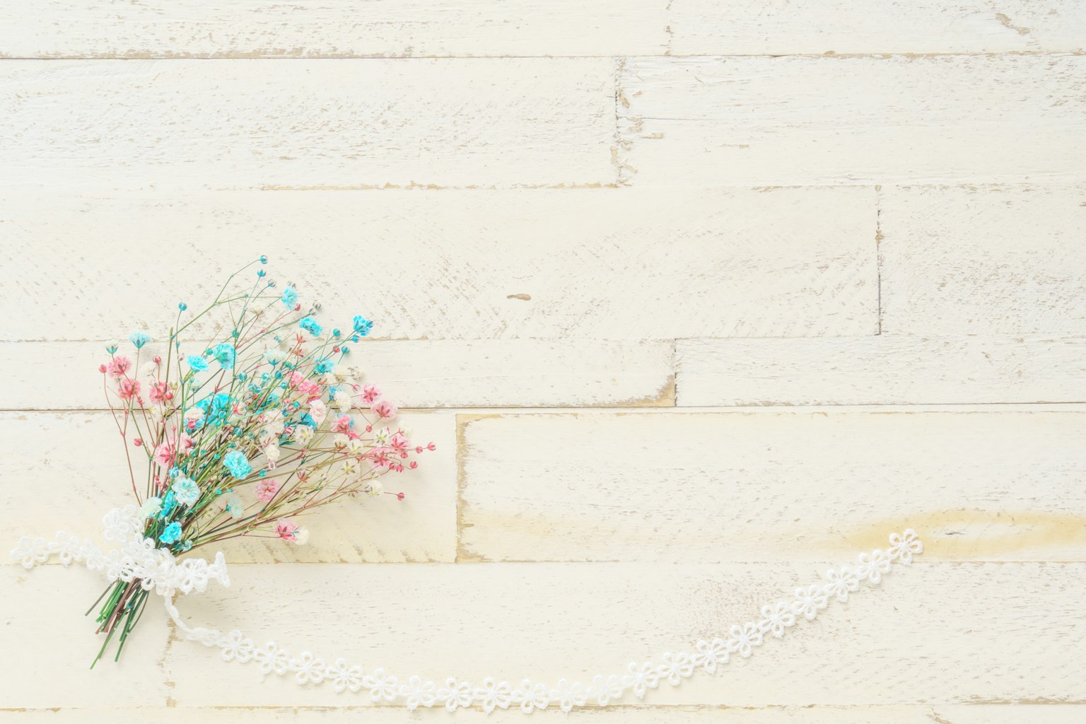 Un pequeño ramo de flores azules y rosas sobre una superficie de madera blanca