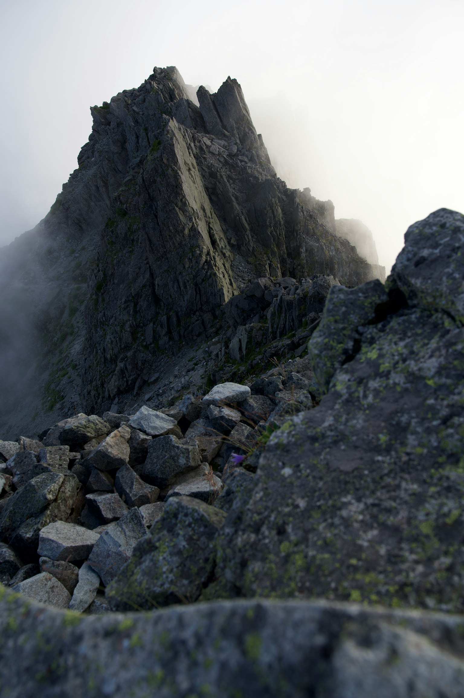 Pic de montagne aigu enveloppé de brume avec terrain rocheux