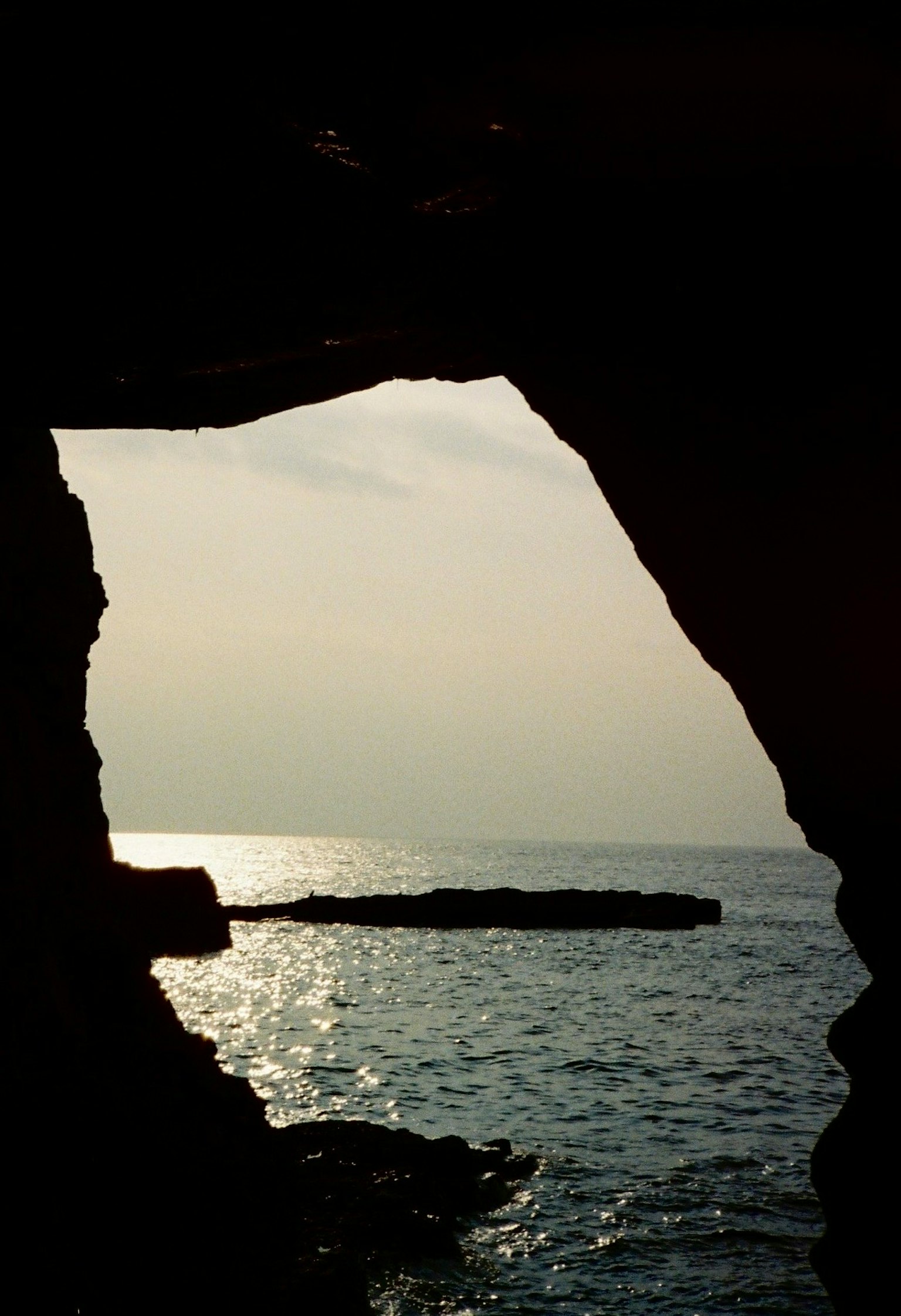Blick aus einer Meereshöhle bei Sonnenuntergang mit ruhiger Wasseroberfläche
