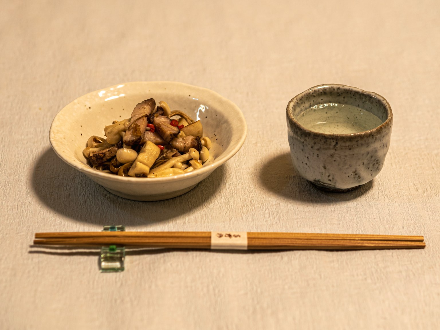 白色碗中裝有混合蘑菇，旁邊是陶瓷清酒杯和木筷子