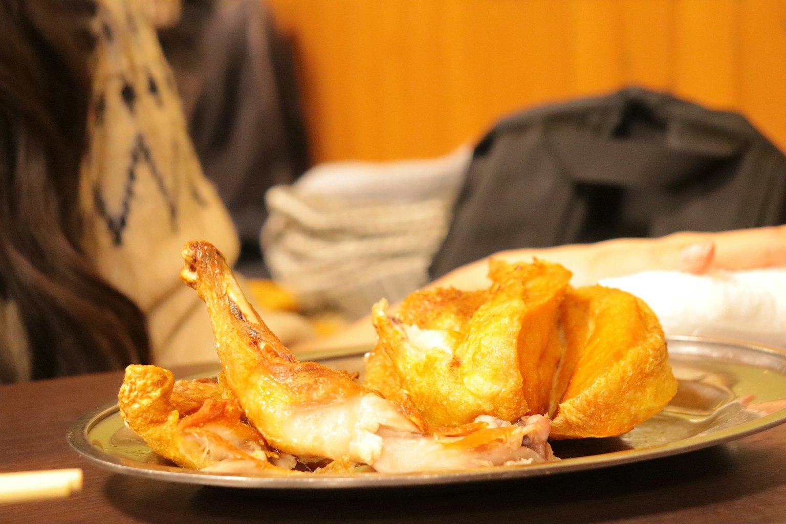 Un plato con un trozo de pollo frito y una mano cercana