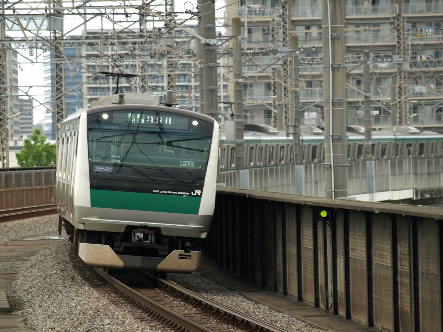 Train au design vert tournant un virage avec des immeubles en arrière-plan