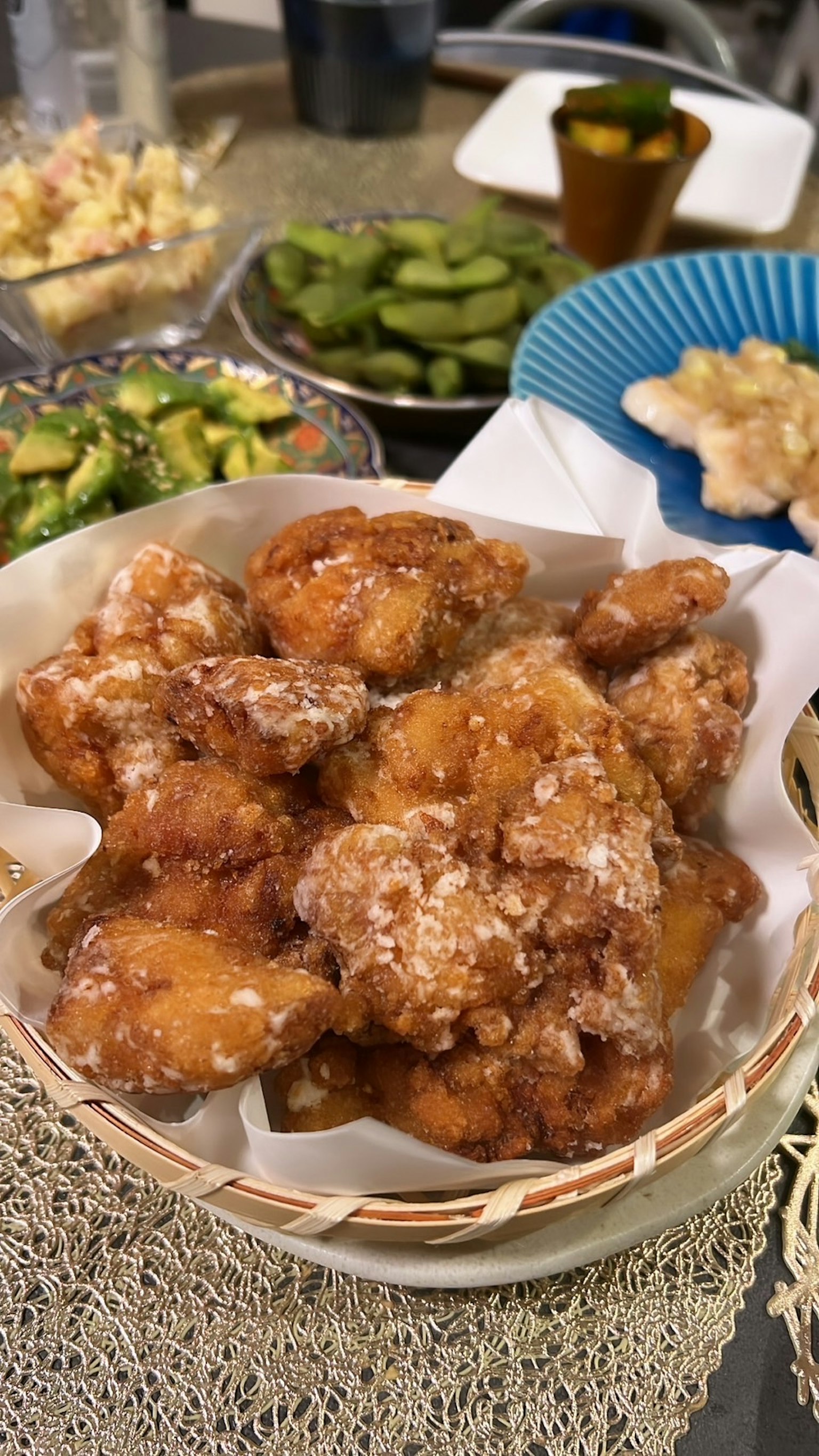 Ein Korb mit frittierten Hähnchenstücken, serviert mit verschiedenen Beilagen im Hintergrund