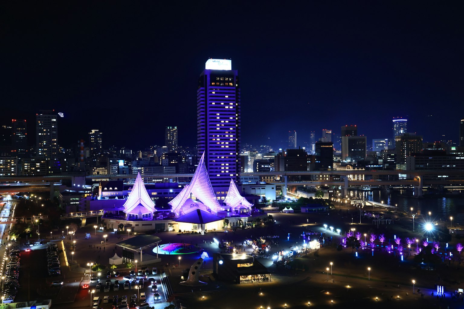 Paisaje urbano nocturno con carpas moradas y un edificio alto