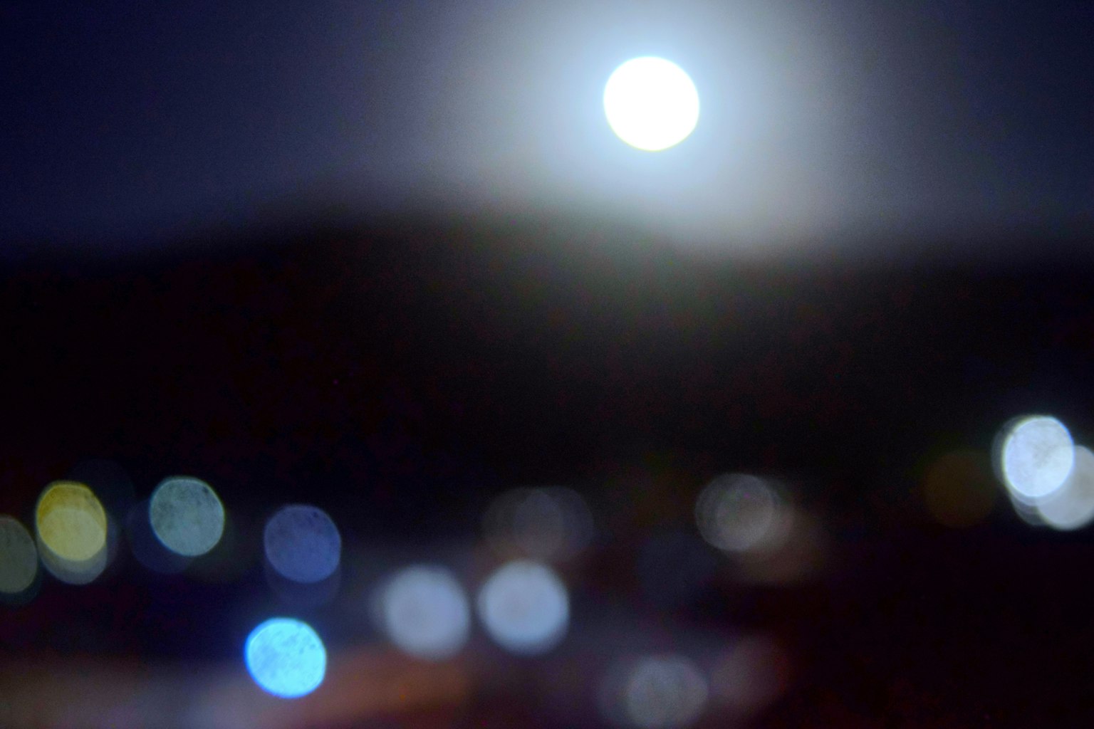 Verschommene Nachtszene mit Mondlicht und verstreuten Lichtpunkten