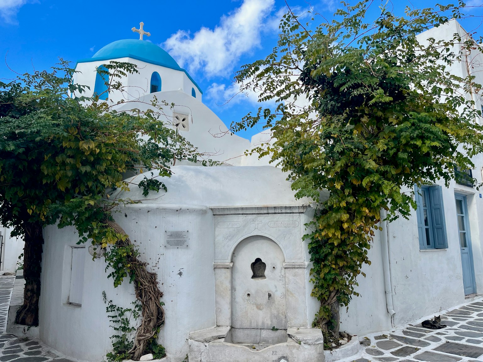Charmant bâtiment blanc avec un dôme bleu et une végétation luxuriante