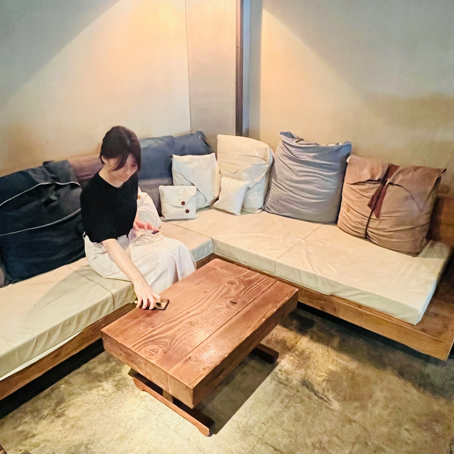 一名女性坐在咖啡馆内的沙发上，沙发上有靠垫