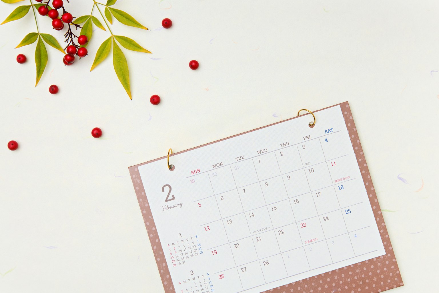 Calendario colocado sobre un fondo blanco con bayas rojas y hojas verdes esparcidas