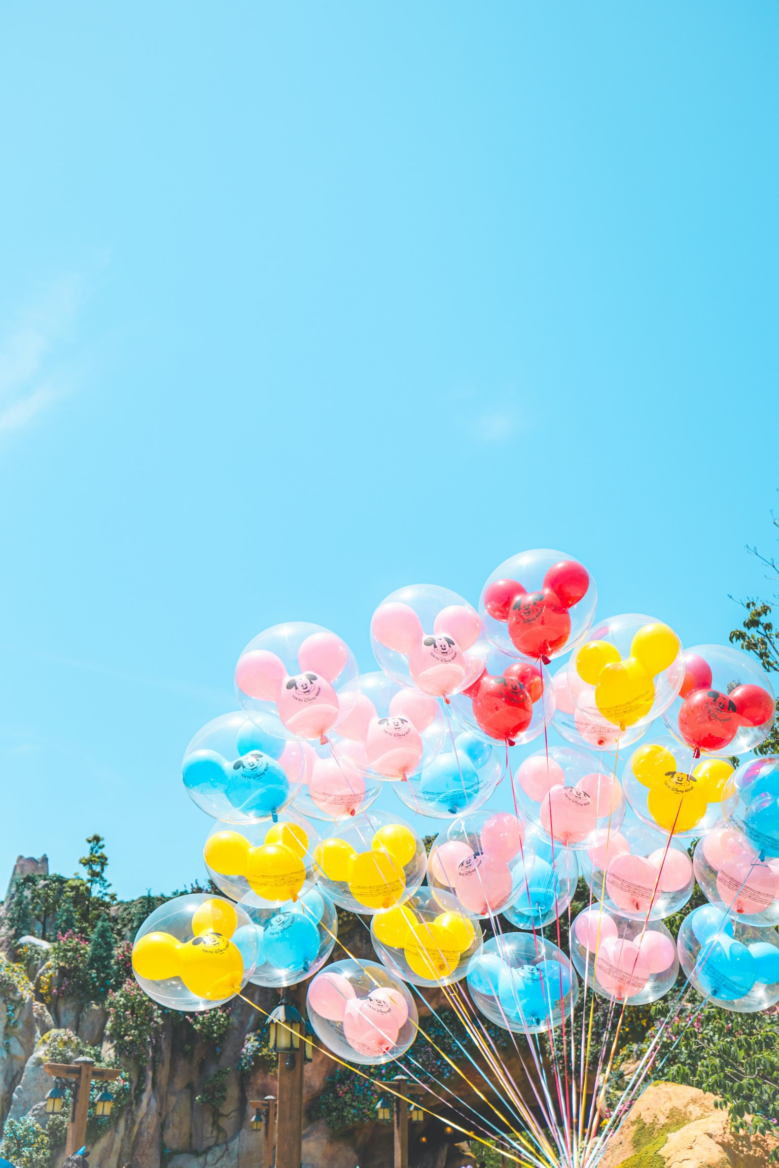 Sekumpulan balon Mickey yang berwarna-warni di bawah langit biru