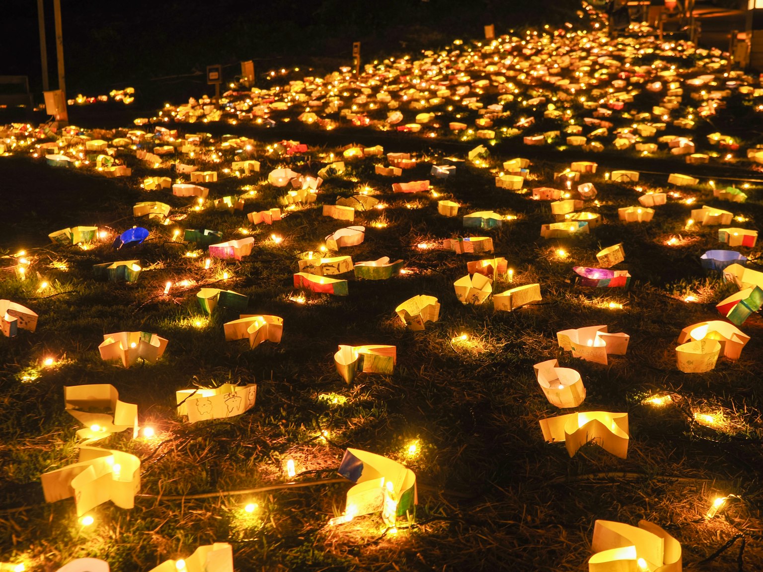 De nombreuses lanternes illuminées éparpillées sur le sol la nuit
