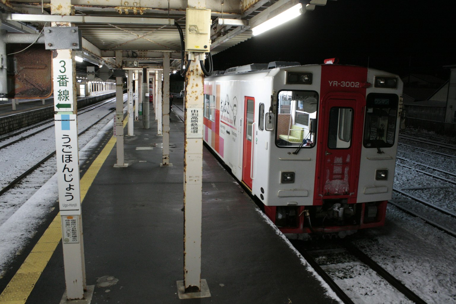 Kereta merah dan putih di stasiun pada malam hari