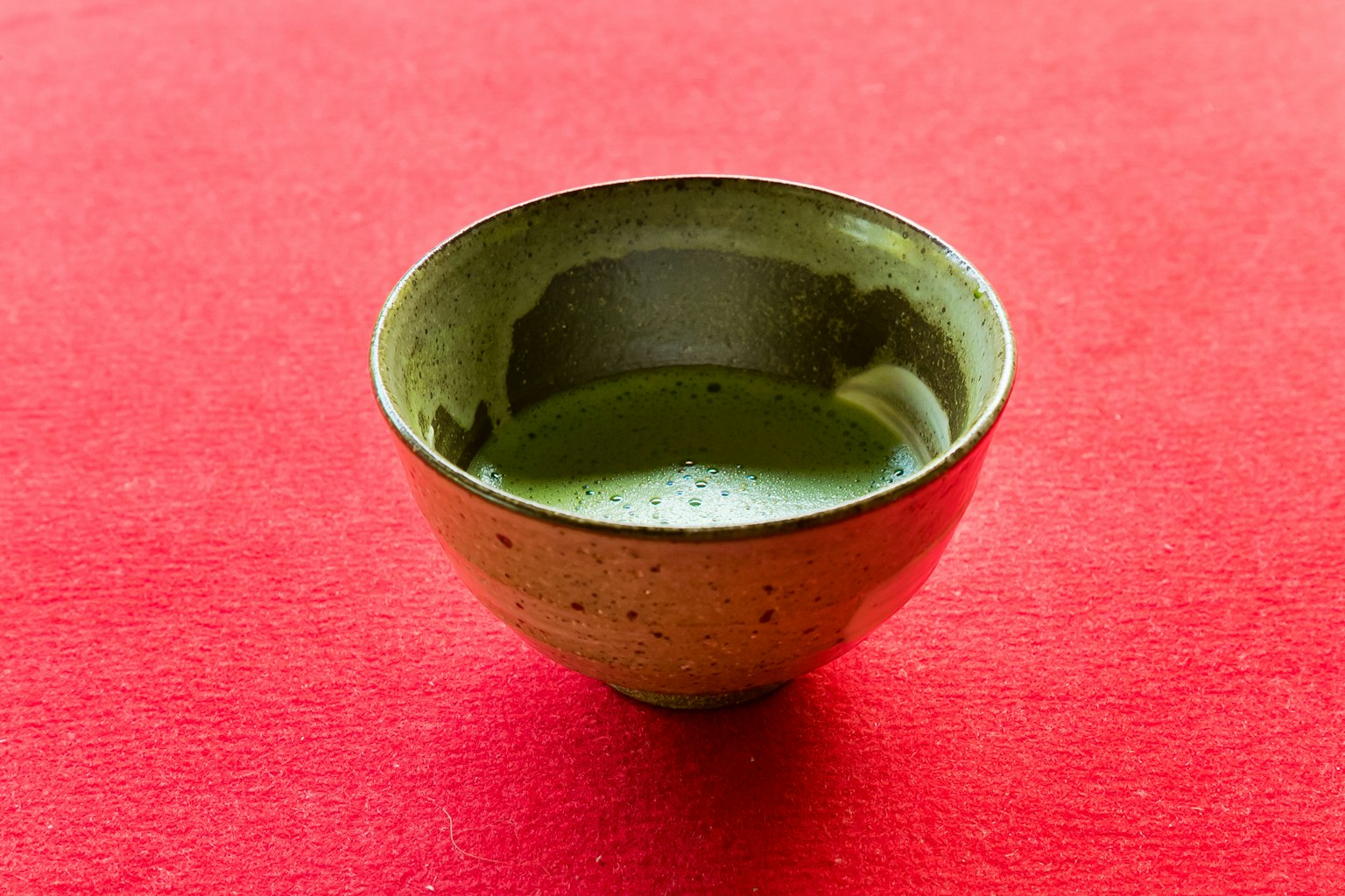 Mangkuk matcha hijau di latar belakang merah