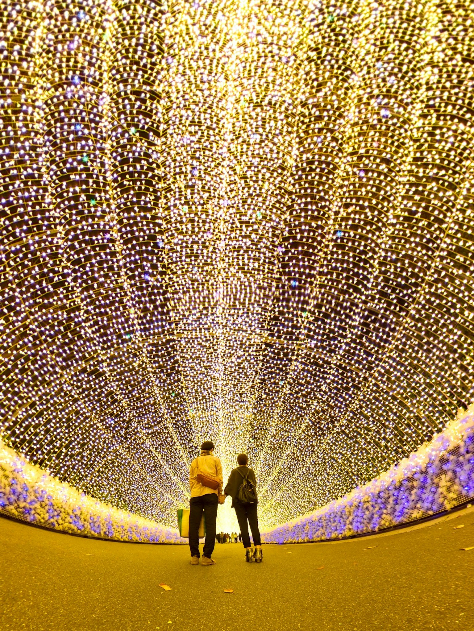 Two people walking in a tunnel of lights