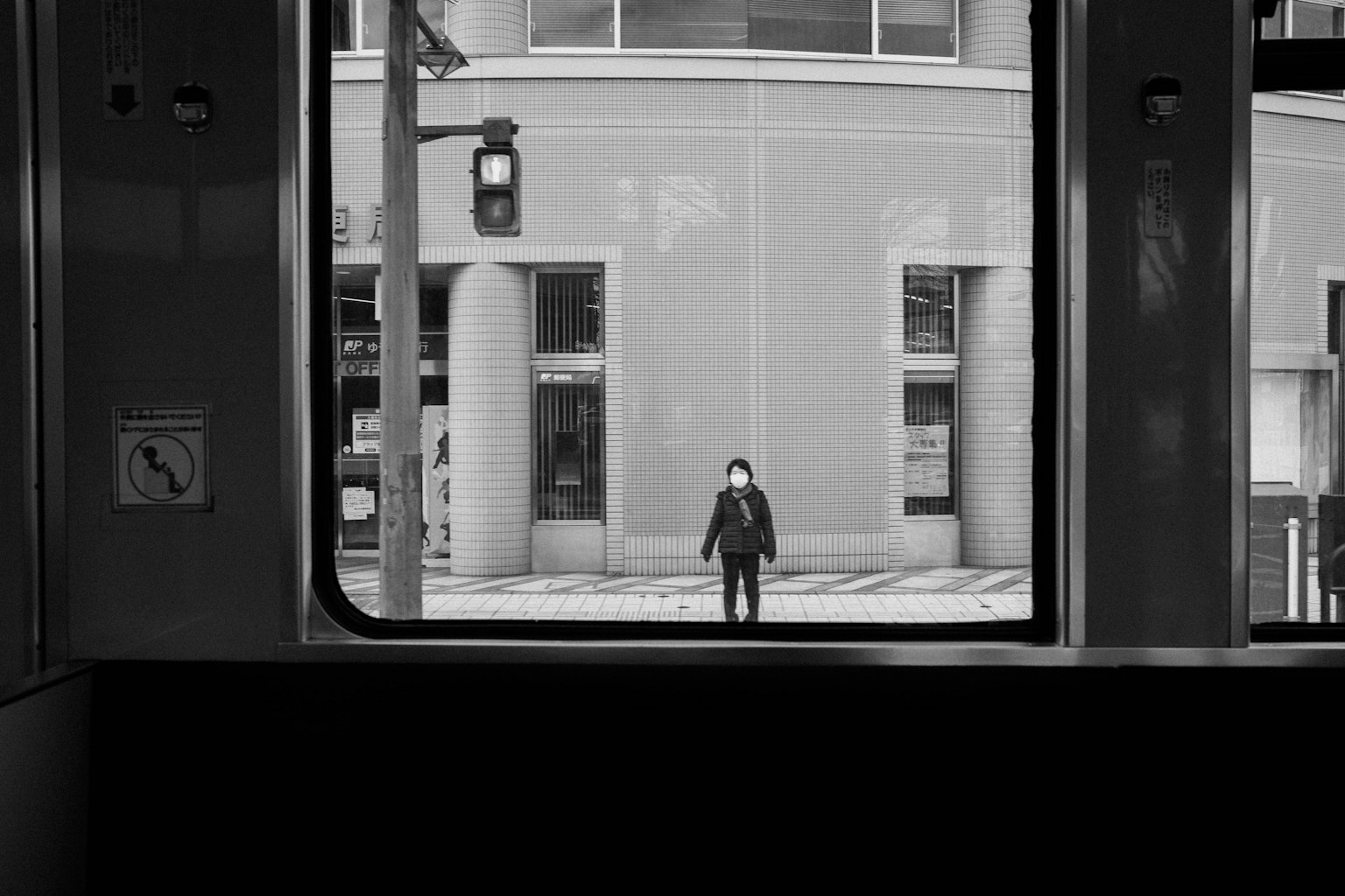 A person standing in front of a building seen through a train window