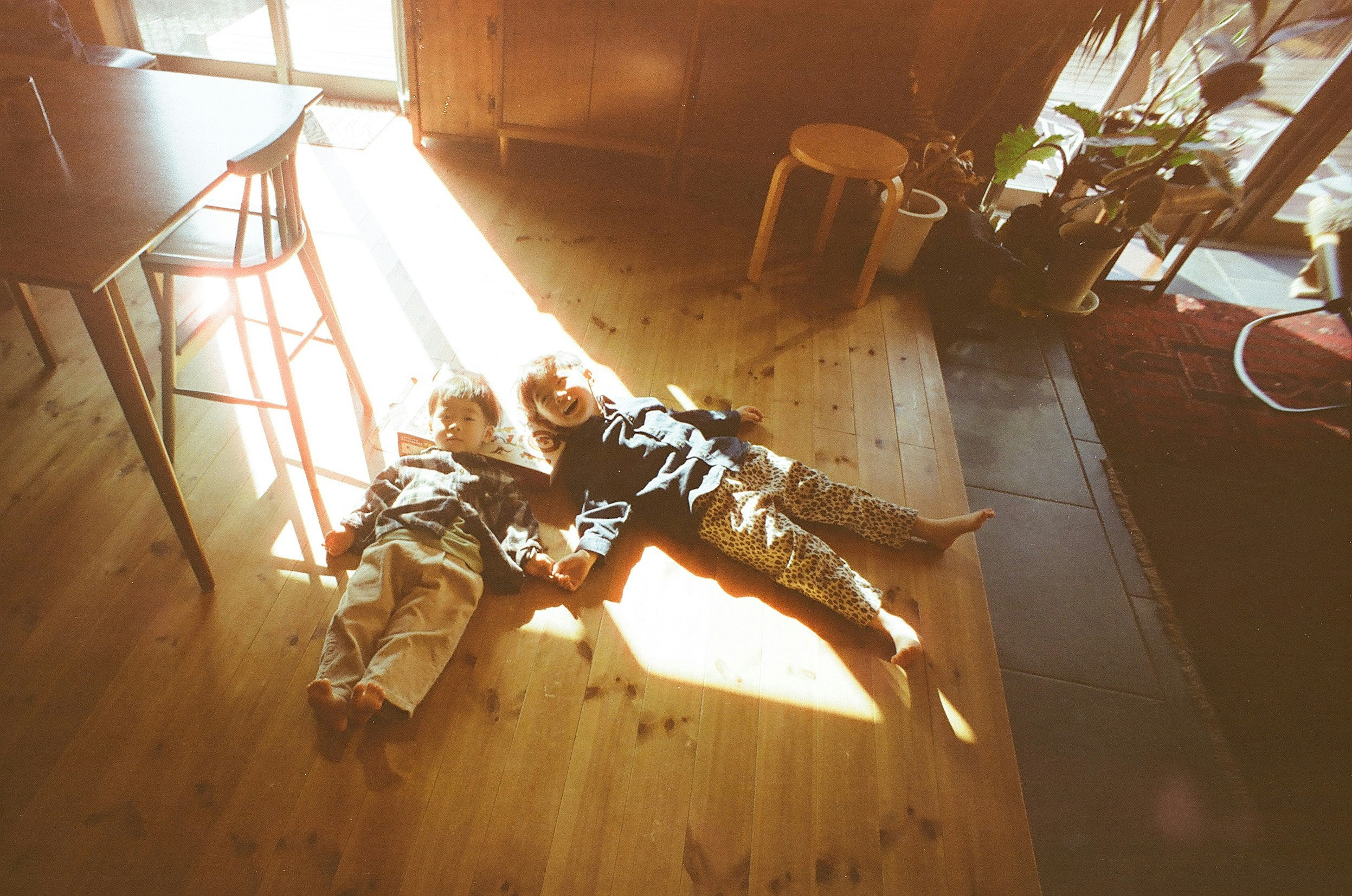 Parent and child relaxing on a wooden floor in bright sunlight