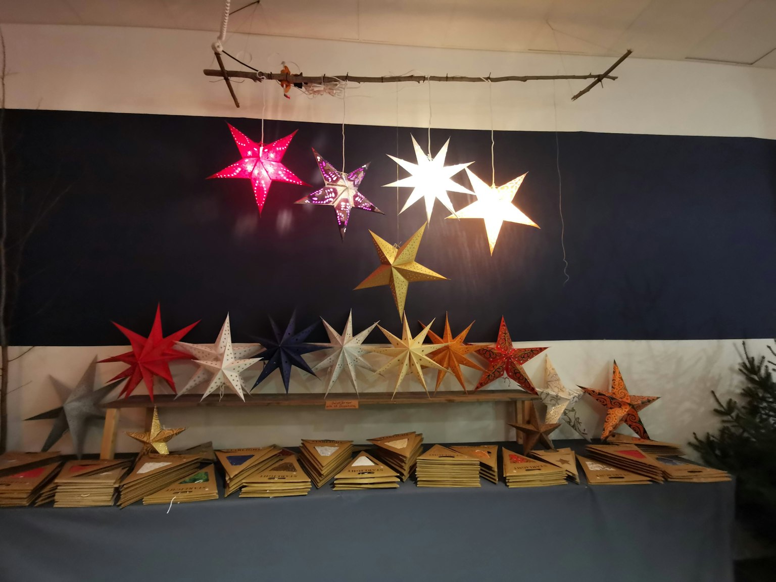 Lampes et décorations en forme d'étoile colorées exposées sur un mur sombre