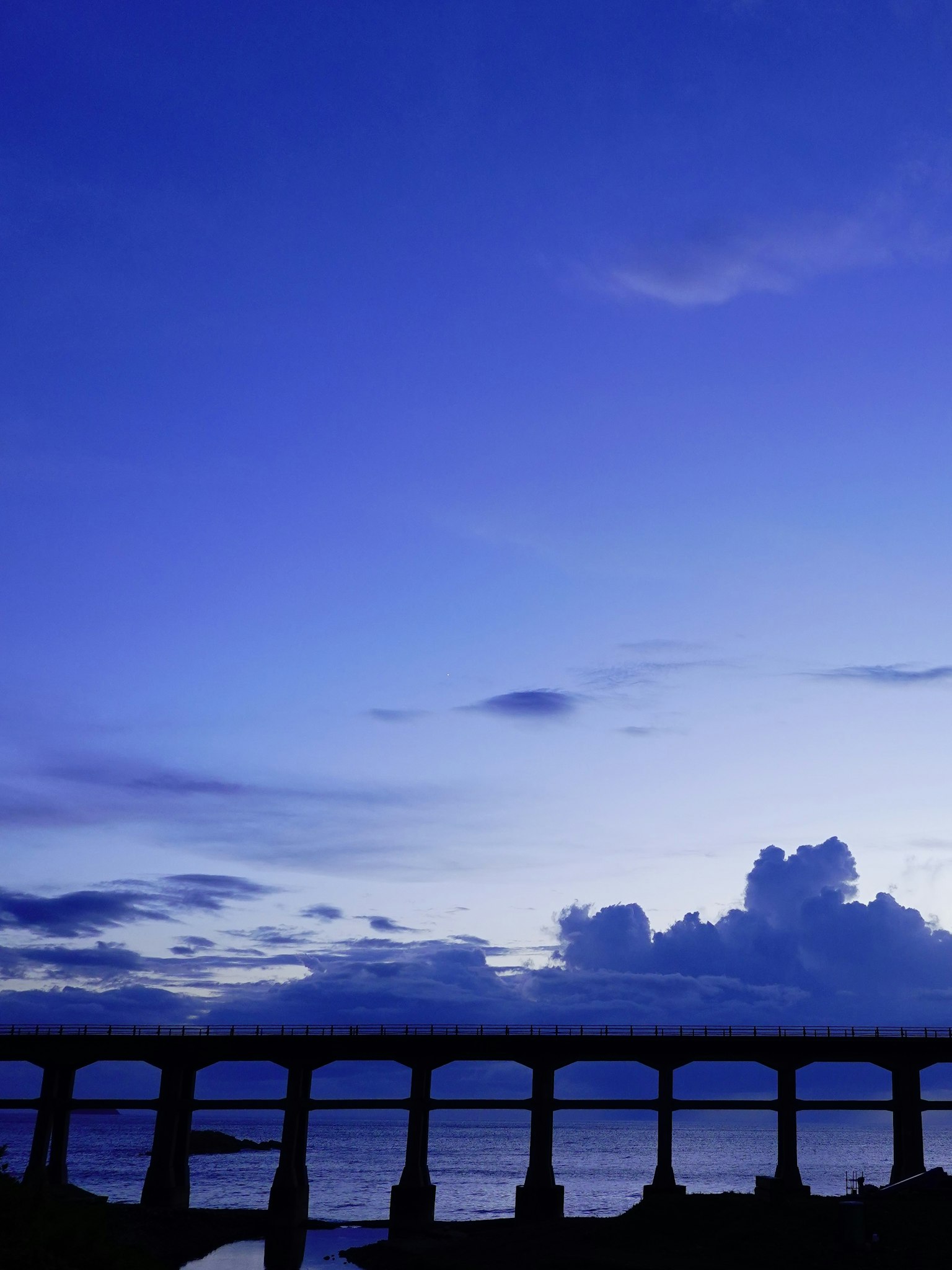 Silueta de un puente contra un cielo azul con nubes