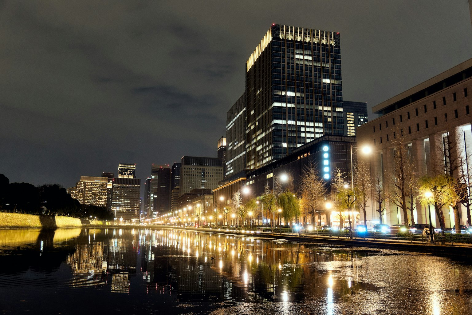 Paisaje urbano nocturno con reflejos de edificios y farolas en el agua una ribera tranquila