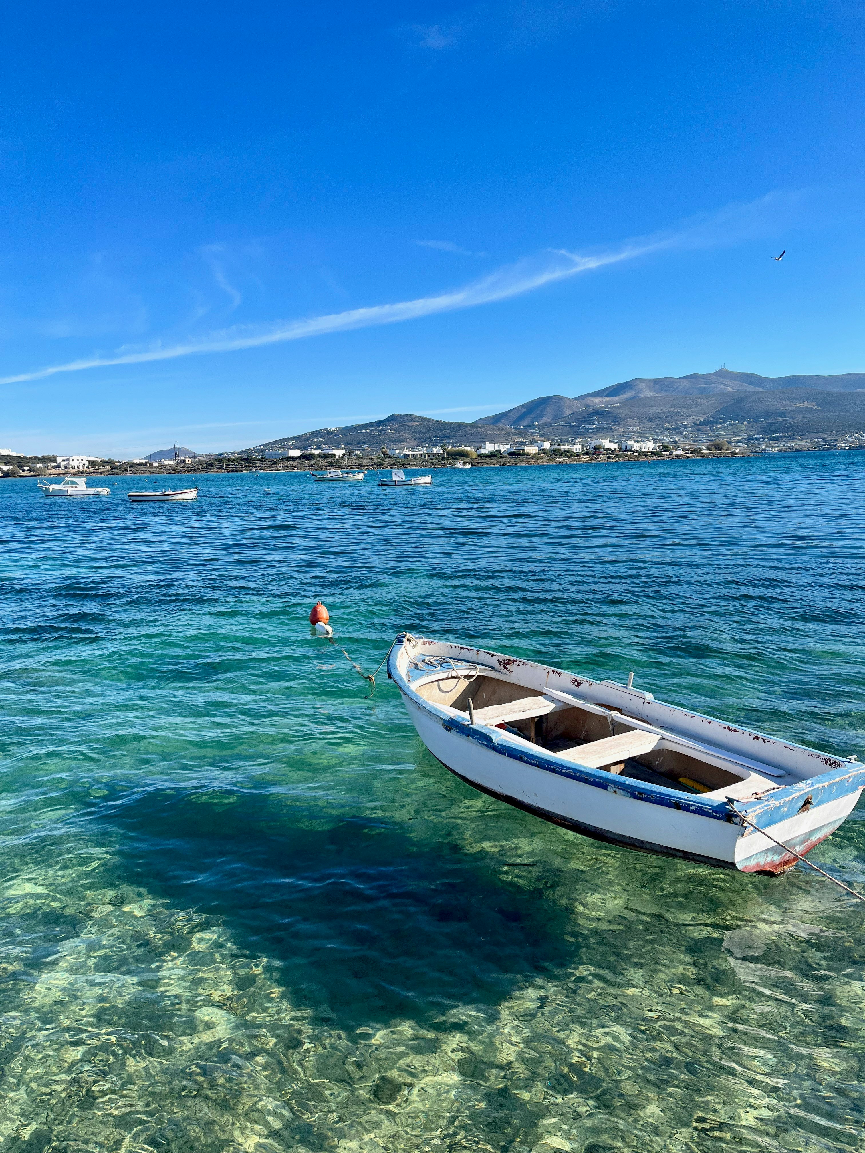 Clear Aegean Sea water with a boat floating in a harbor scene