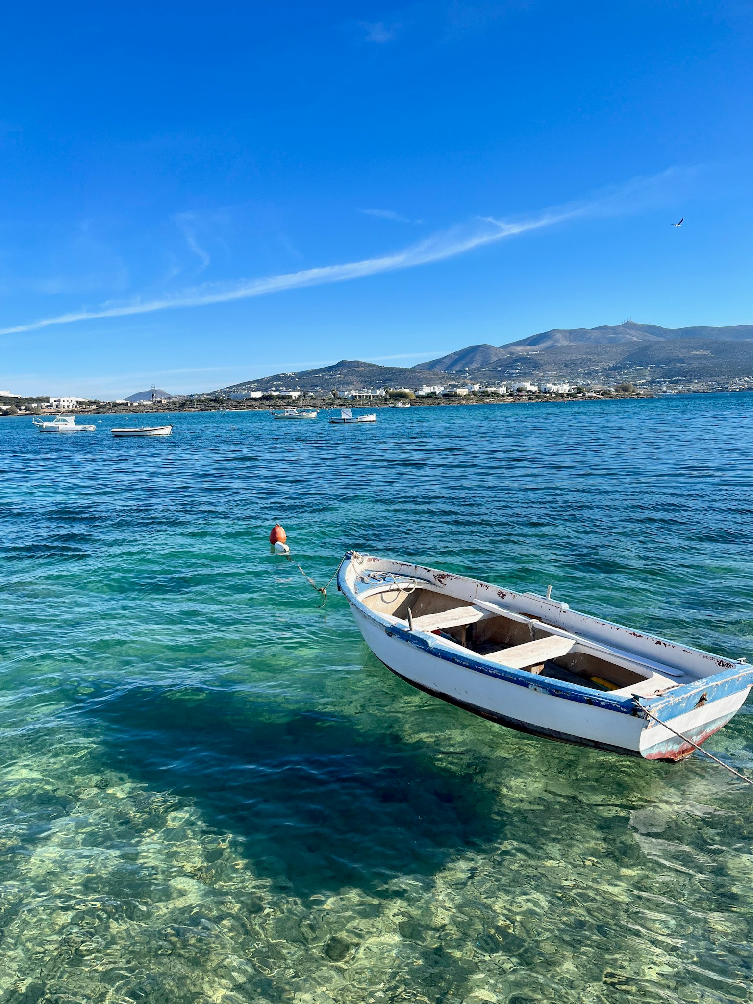 Weißes Boot, das auf blauem Meer mit fernen Bergen schwimmt