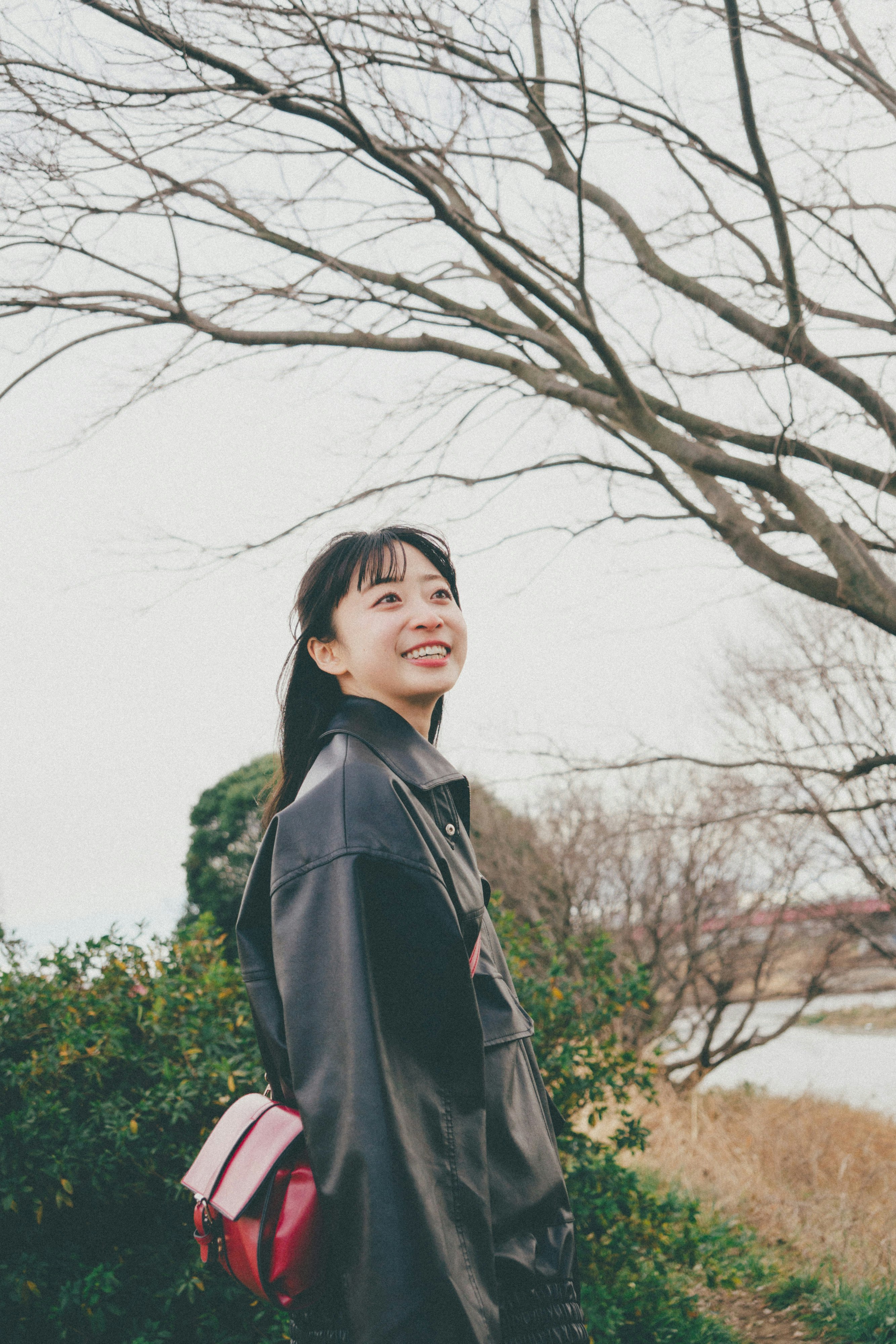 木々の並ぶ公園でコートを着た女性