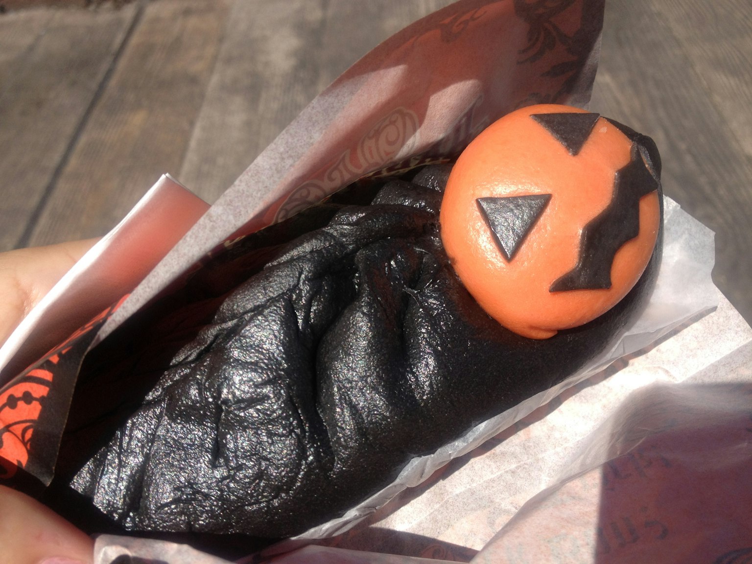 Black bun with orange pumpkin topping featuring a jack-o'-lantern design