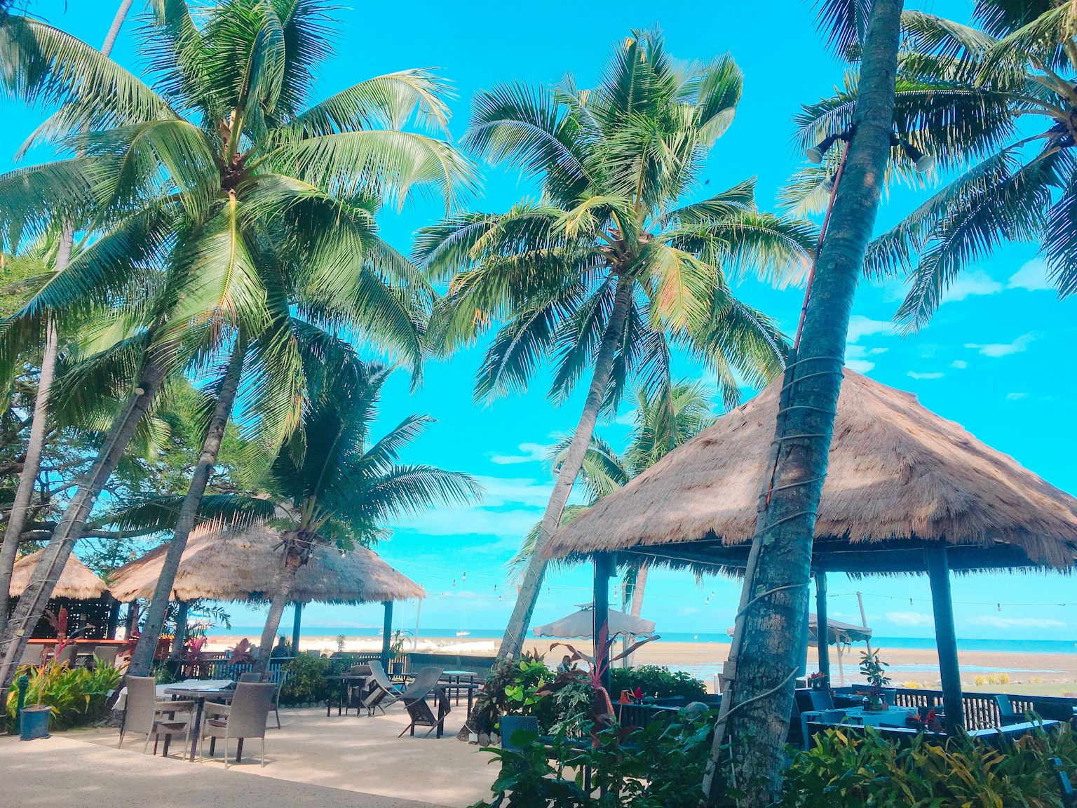 Zone de repos au bord de la plage entourée de palmiers et d'un ciel bleu