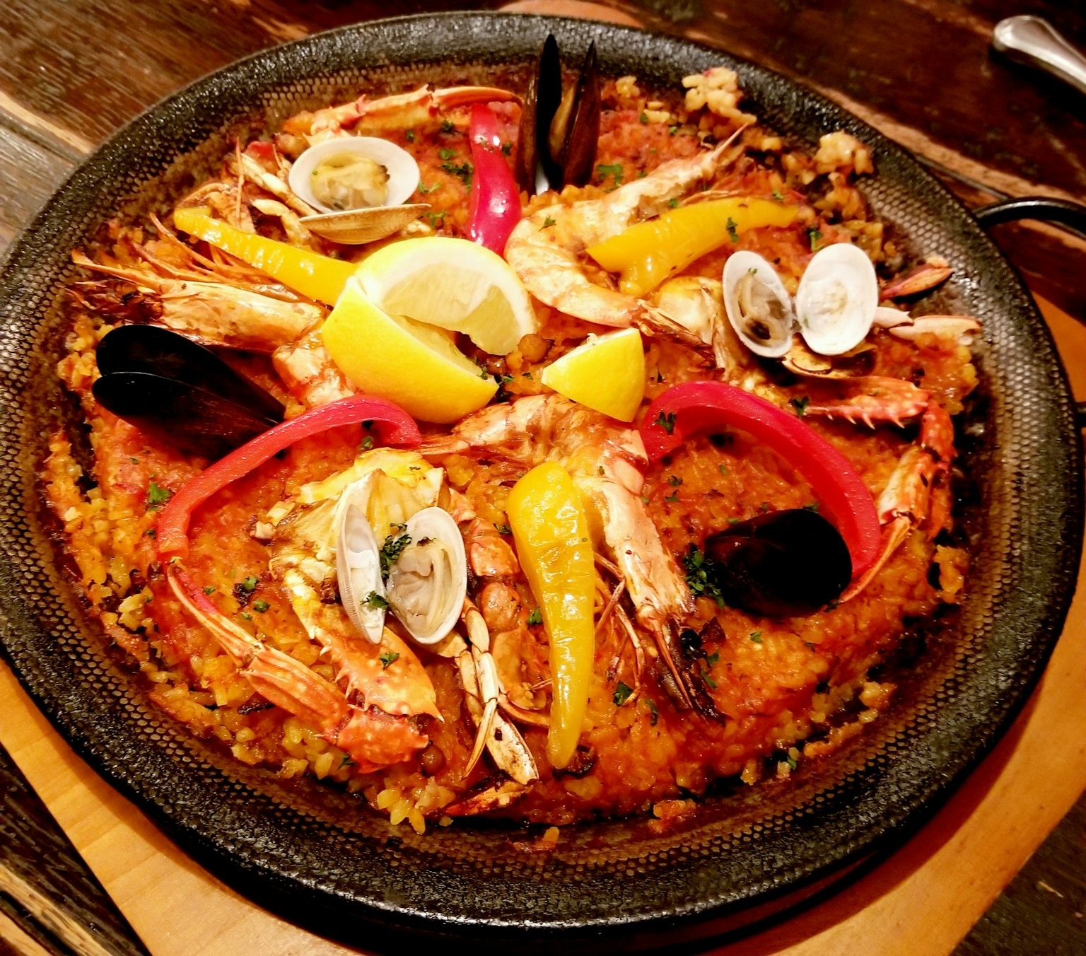 Une paella colorée garnie de crevettes et de coques avec du citron et des poivrons