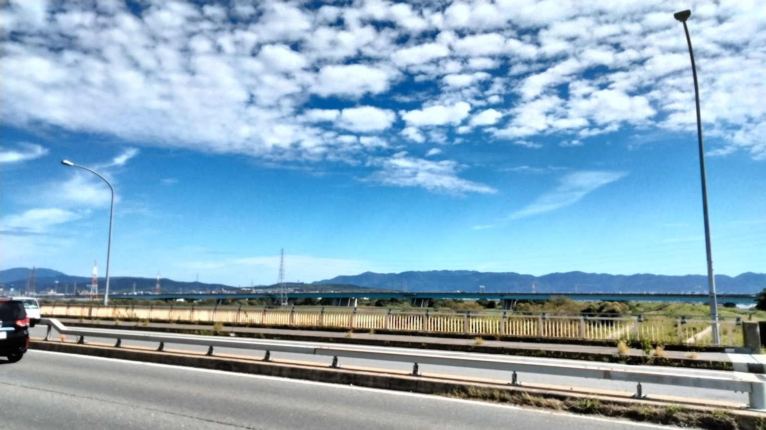 Scenic view with blue sky and white clouds featuring a highway and mountains