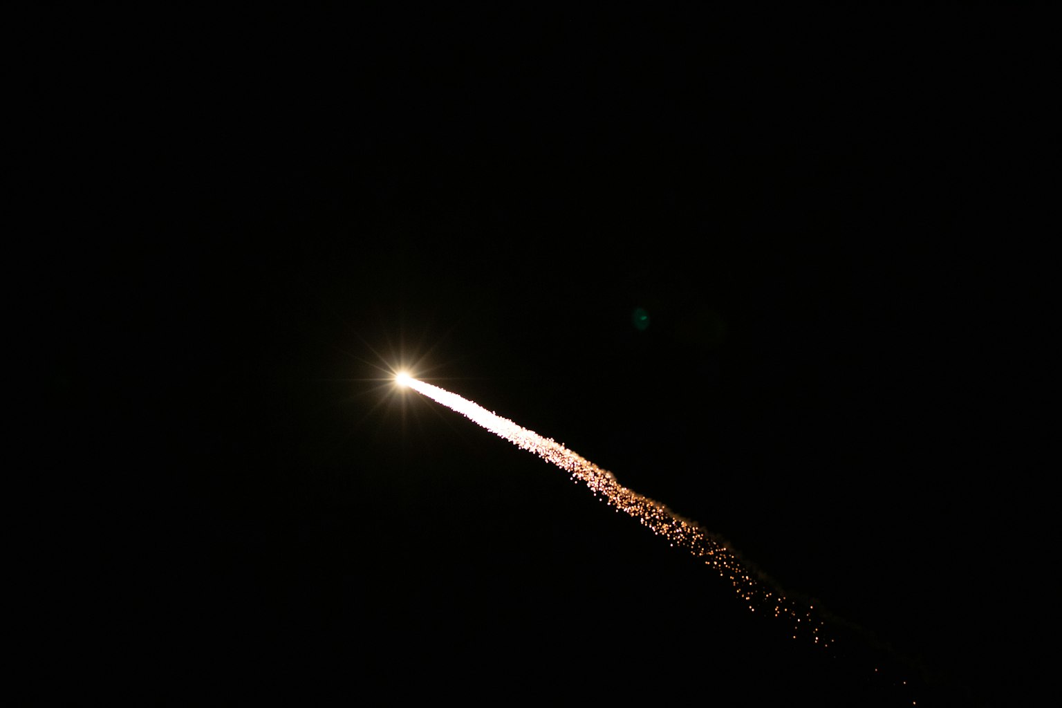 火箭發射進入夜空，伴隨著明亮的光和飛濺的火花