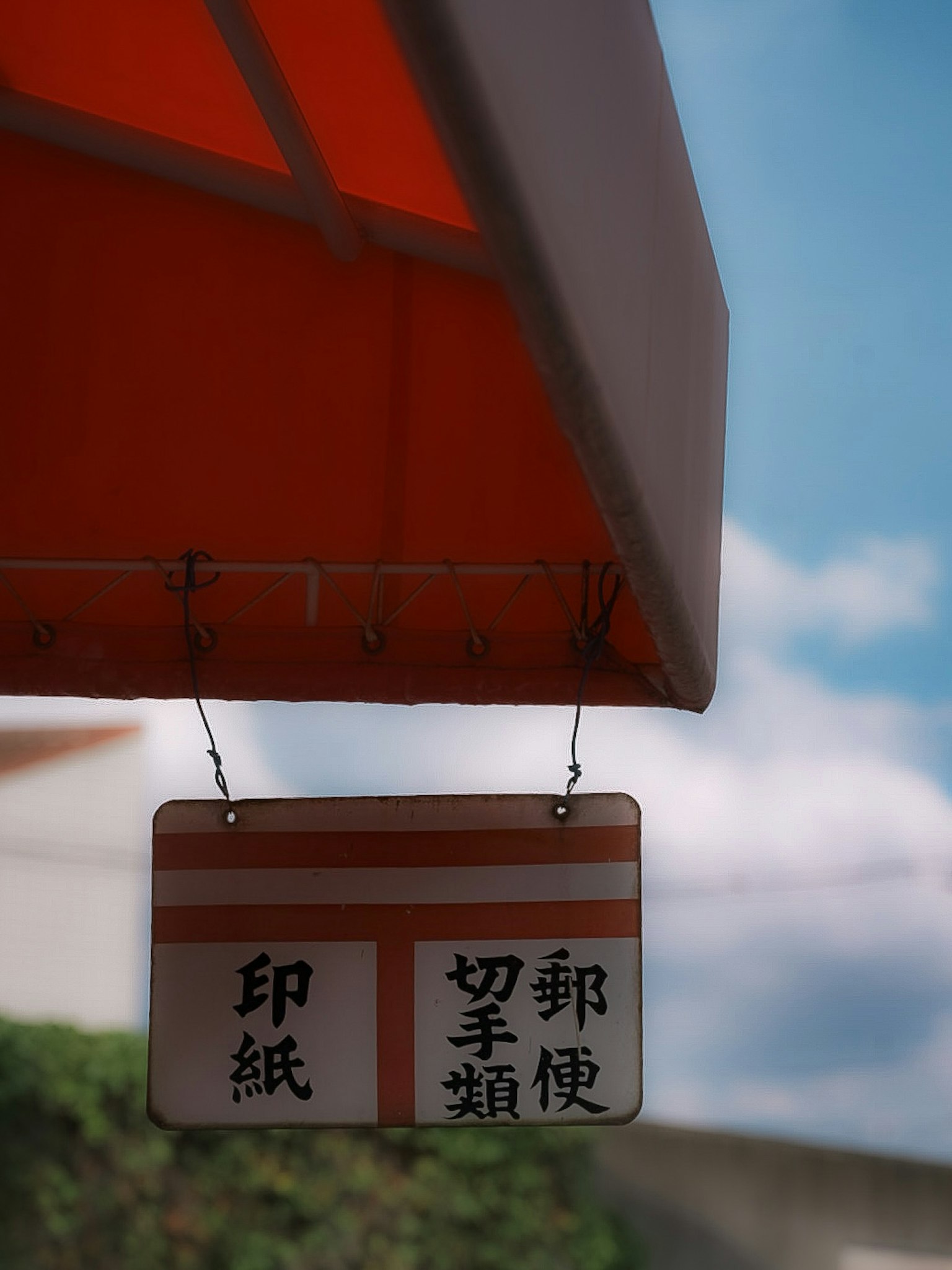 A sign hanging under an orange awning with Chinese characters