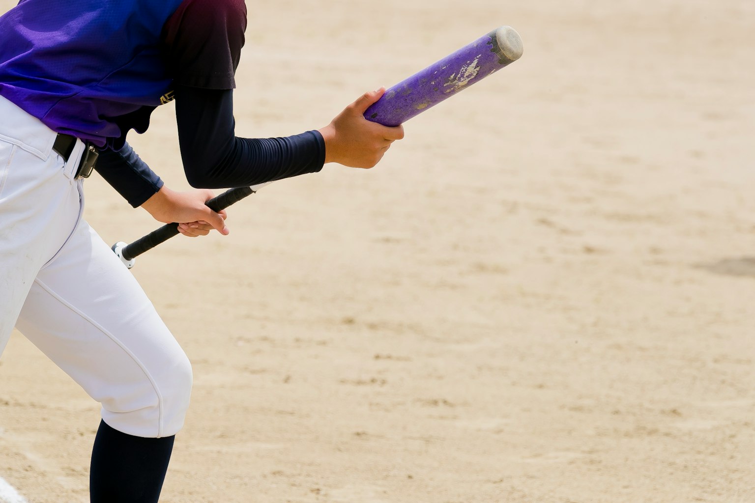 Primo piano di un giocatore di baseball che tiene una mazza viola