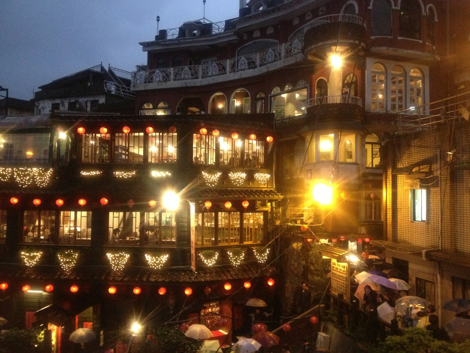 Magnifiques maisons de thé illuminées au crépuscule avec des parapluies le long de la rue