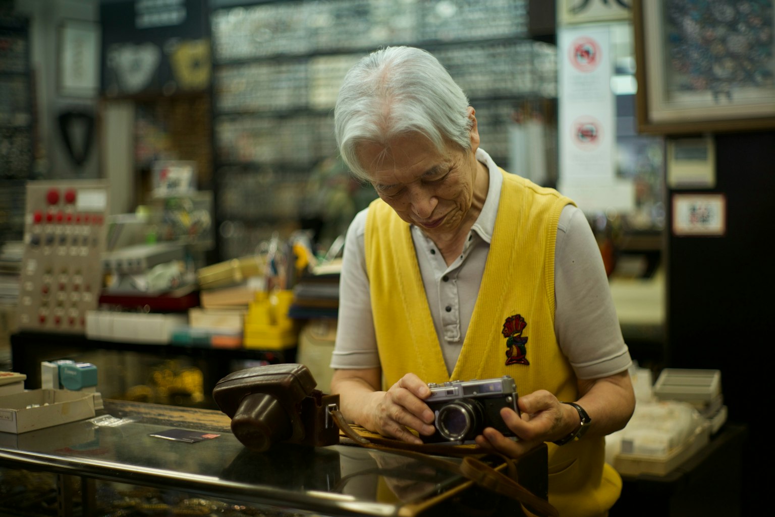 Älterer Mann mit einer Kamera in einem Vintage-Shop umgeben von verschiedenen Gegenständen