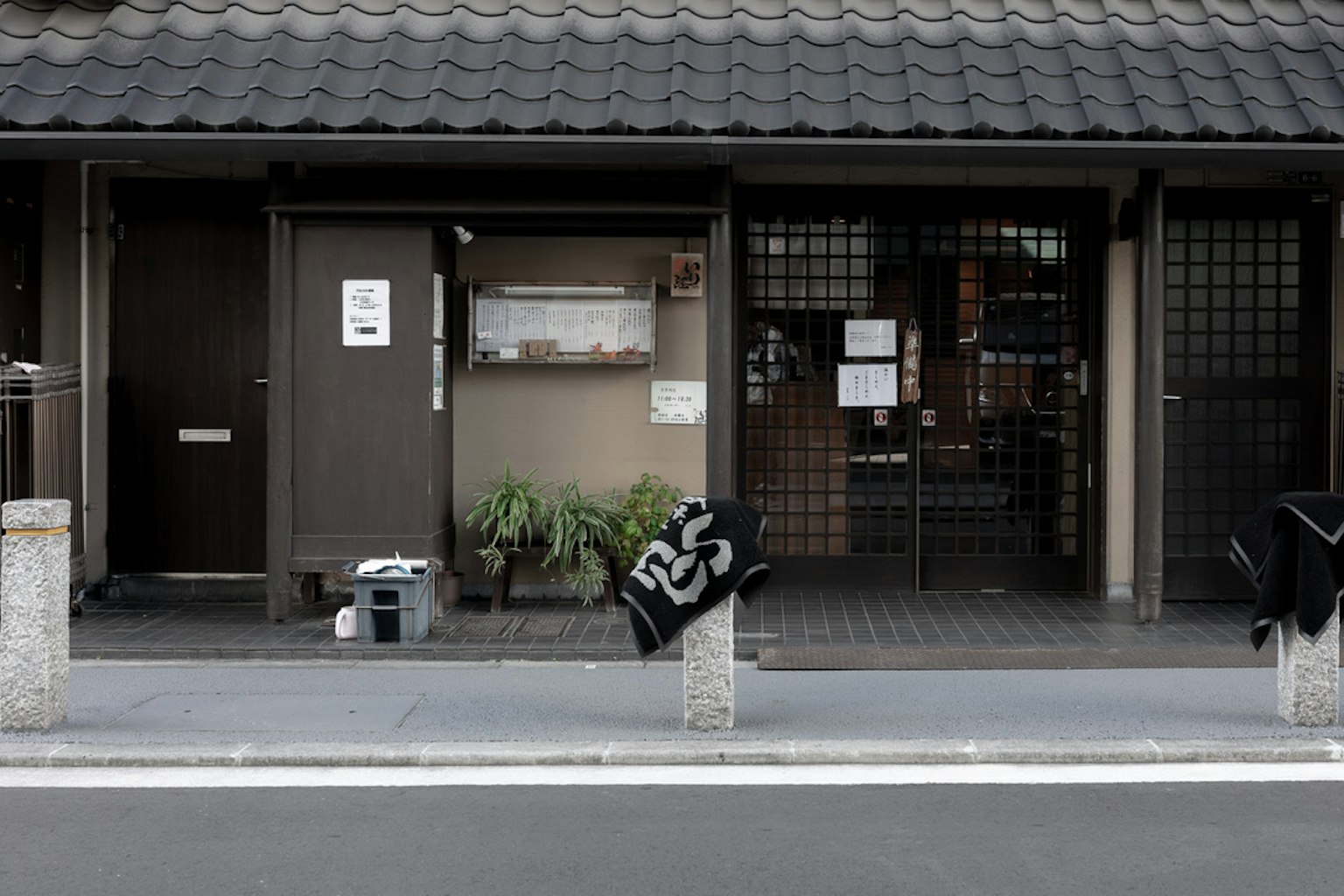 古老日本房屋的外观，木门，黑色瓦屋顶，外面放置植物